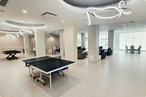 Expansive open-concept floor plan featuring large-format tile flooring, sculptural LED pendant lighting, and recessed circular ceiling detailing