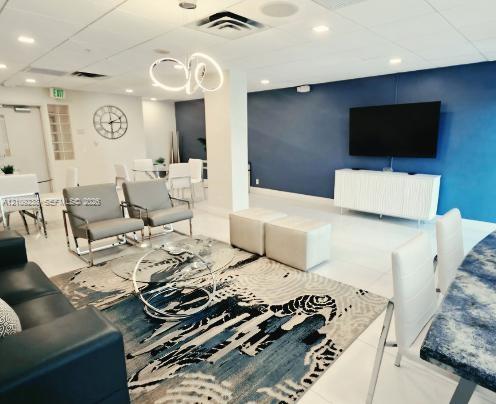 Open-concept interior featuring large-format tile flooring, recessed lighting, a modern circular pendant light fixture, and a deep blue accent wall