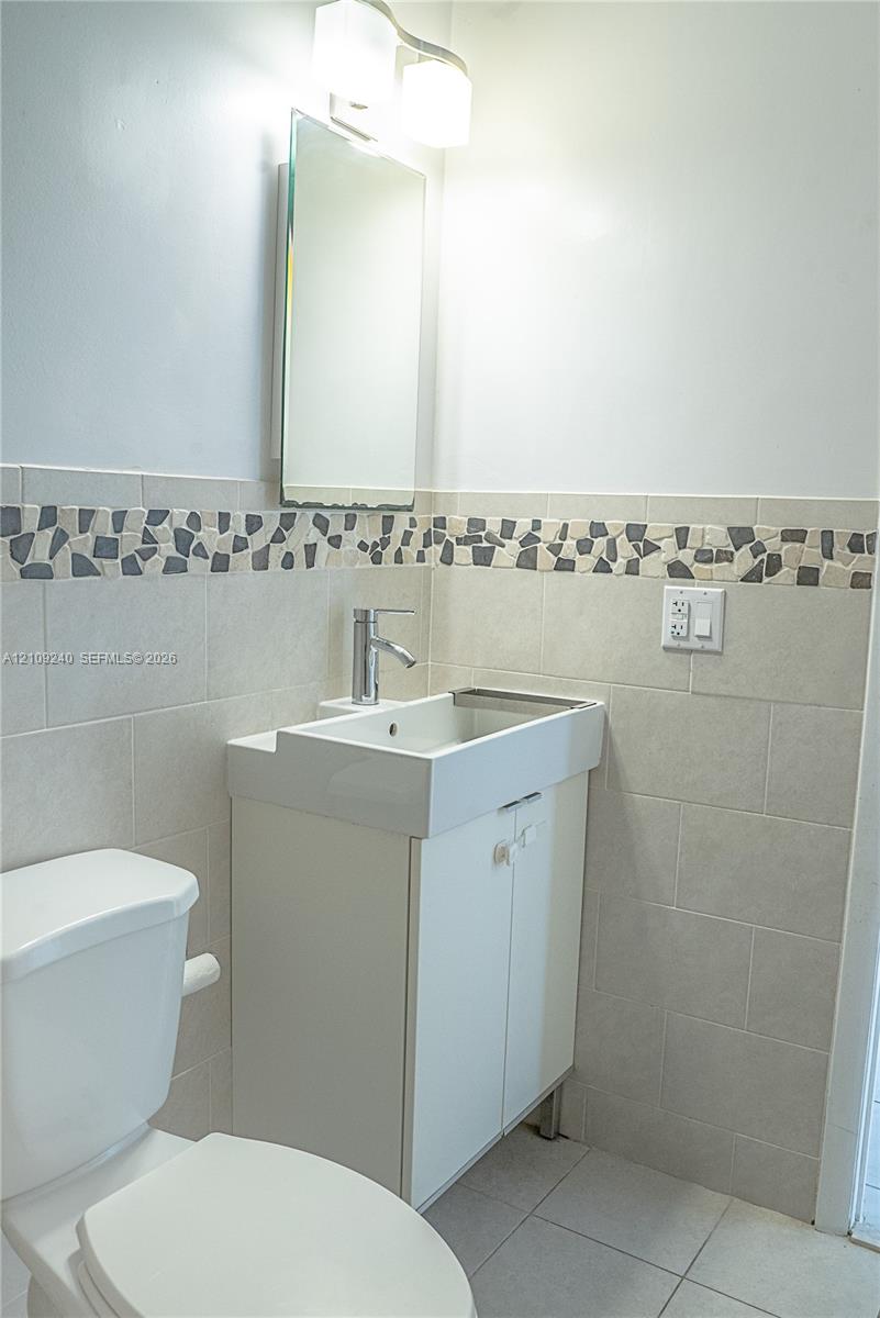 Wall-mounted vanity featuring a rectangular integrated sink, polished chrome faucet, tiled backsplash with mosaic accent border, and dual-light vanity fixture