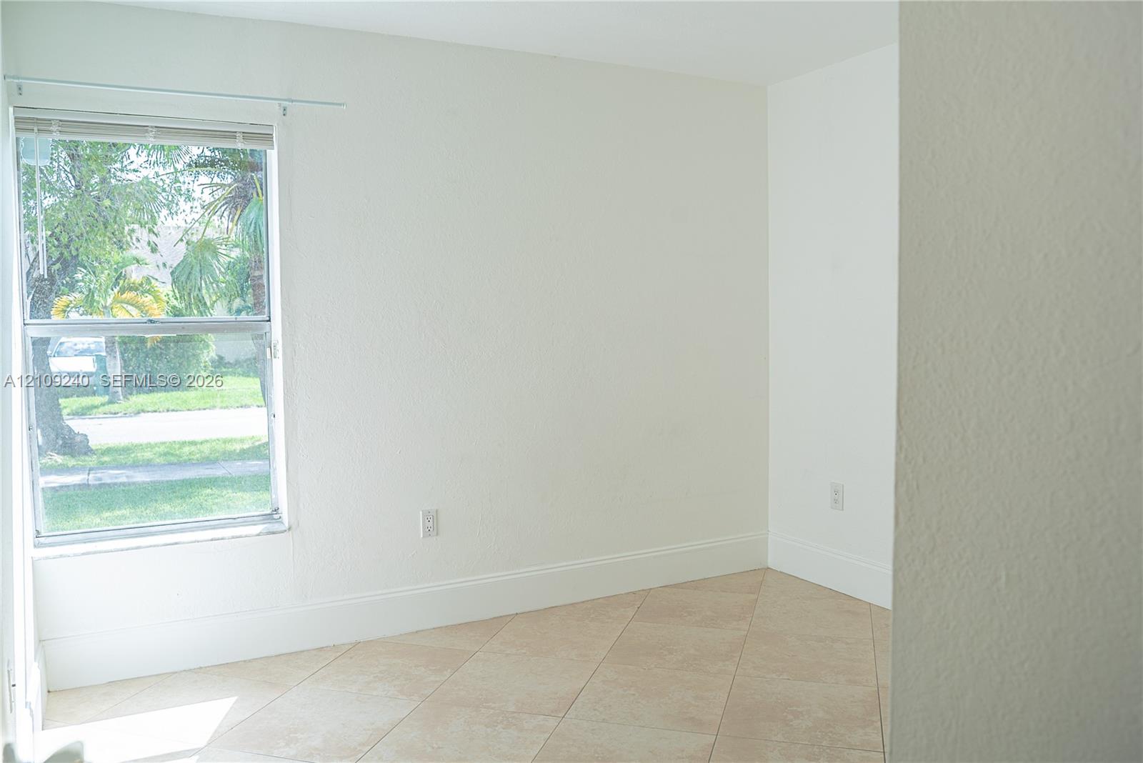 Neutral-toned wall finish, light-colored tile flooring, and single-hung window with a metal frame