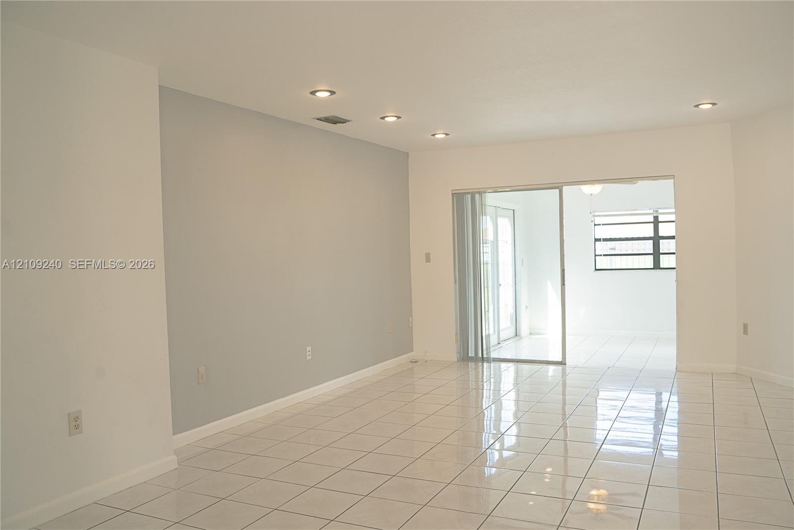 Interior space featuring neutral wall tones, polished tile flooring, recessed ceiling lighting, and a glass sliding door