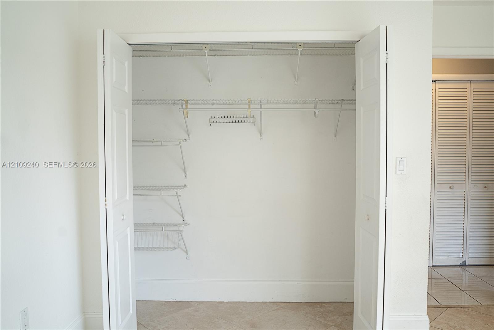 Reach-in closet featuring dual bifold doors, white wire shelving, integrated hanging rods, and an overhead storage shelf