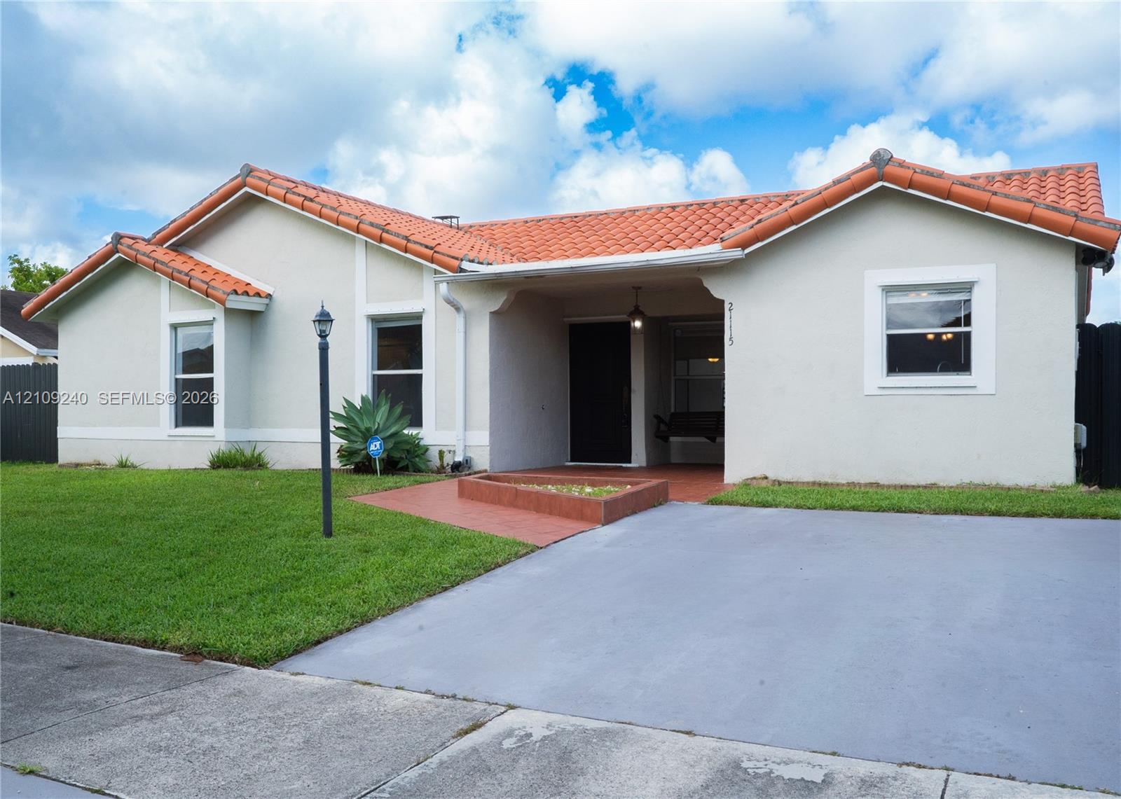 Stucco exterior residence featuring a terracotta-tiled roof, covered entryway, and concrete driveway Stucco exterior residence featuring a terracotta-tiled roof, covered entryway, and concrete driveway