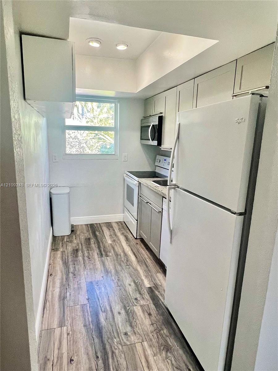 Kitchen featuring wood-finish flooring, recessed lighting, stone-surfaced countertops, and white cabinetry