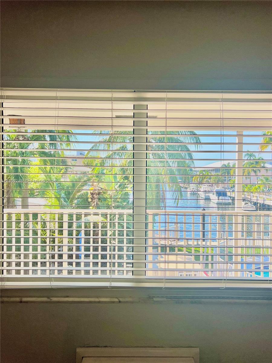 Horizontal window blinds, exterior balcony with white railings, and direct water frontage featuring a canal