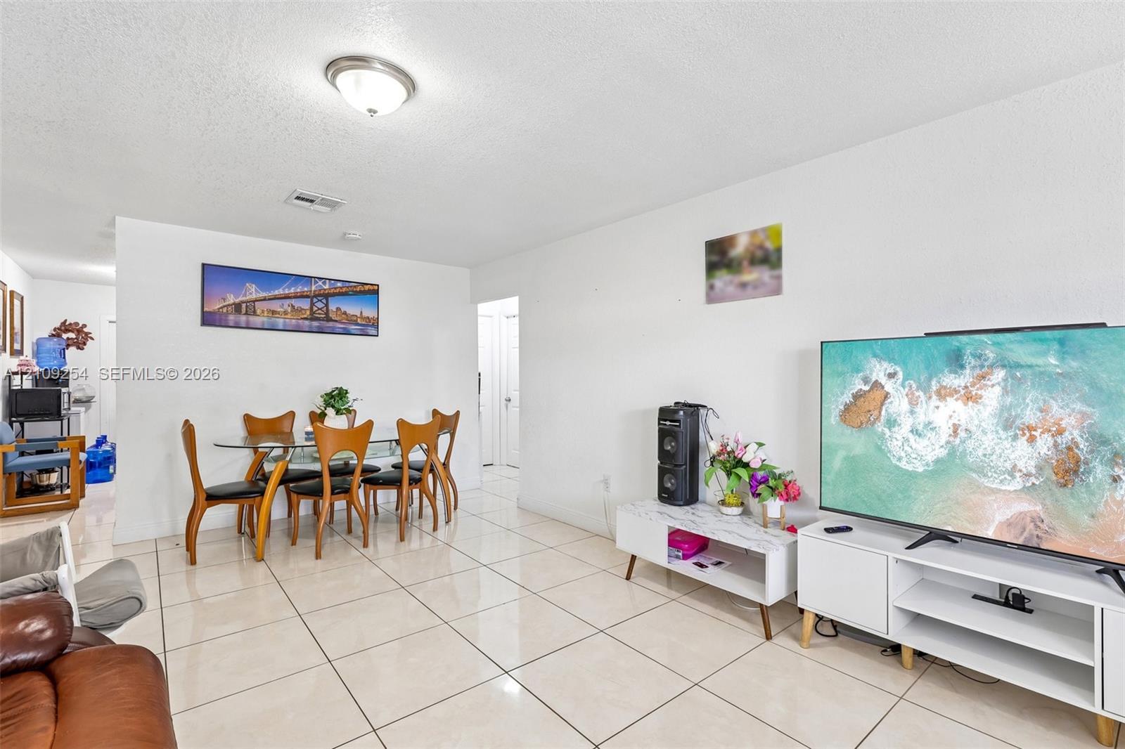 Neutral-toned tile flooring throughout an open-concept living area featuring a central dome light fixture Neutral-toned tile flooring throughout an open-concept living area featuring a central dome light fixture
