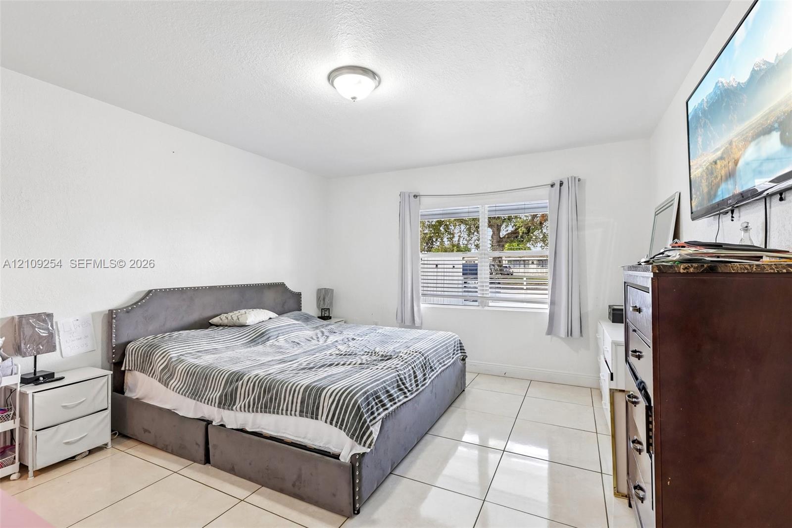 Spacious room featuring large-format tile flooring, smooth-finish walls, and a multi-pane window with natural light