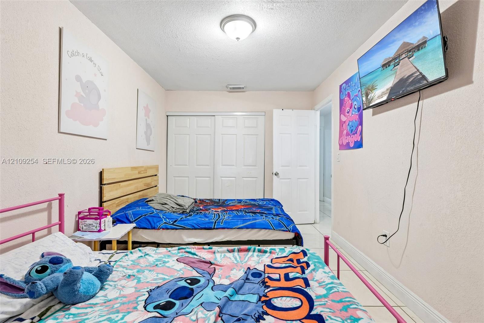Room featuring light-toned neutral walls, white sliding-panel closet doors, and tile flooring