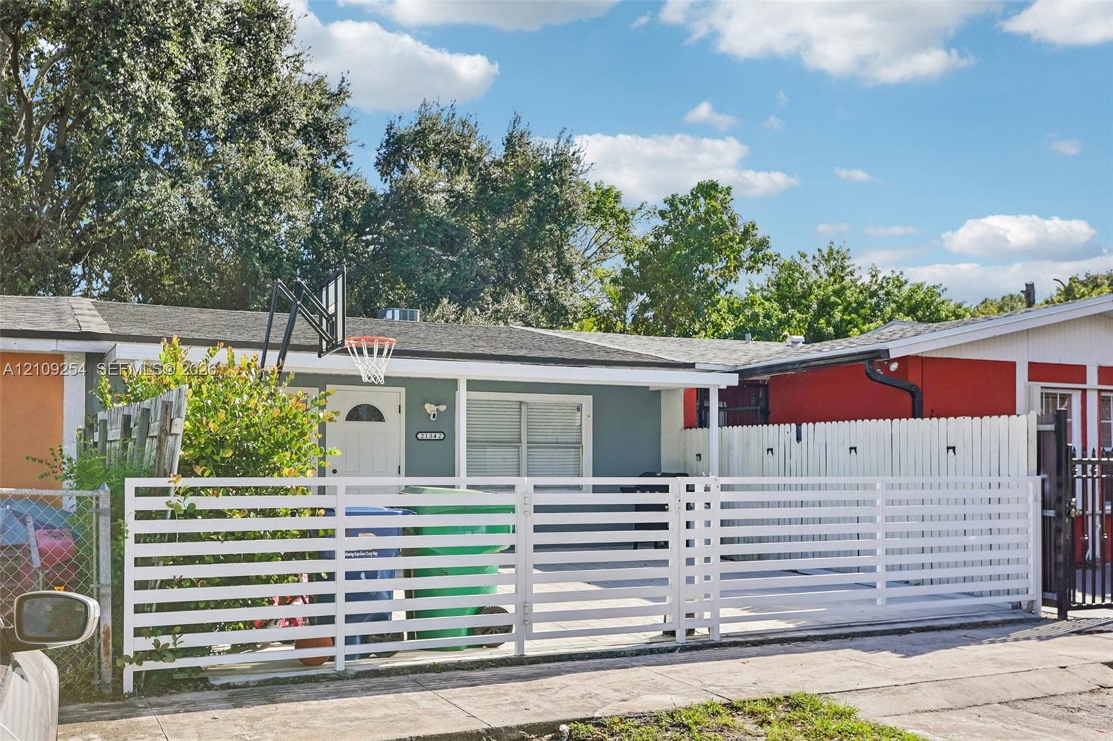 Single-story exterior featuring a horizontal slat privacy fence, concrete paved driveway, and mature landscaping Single-story exterior featuring a horizontal slat privacy fence, concrete paved driveway, and mature landscaping