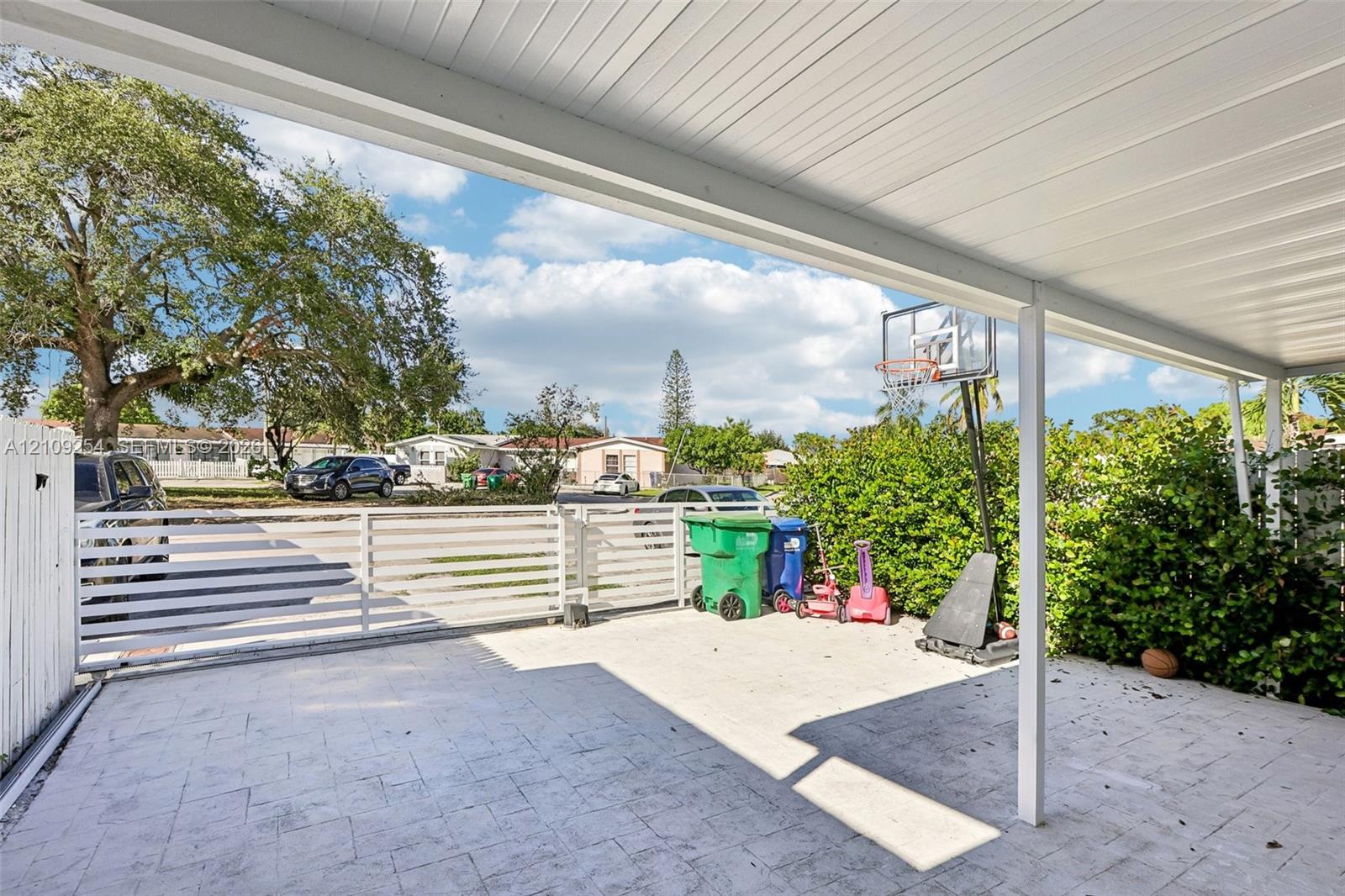 Covered patio featuring a paved surface and white horizontal-slat perimeter fencing Covered patio featuring a paved surface and white horizontal-slat perimeter fencing