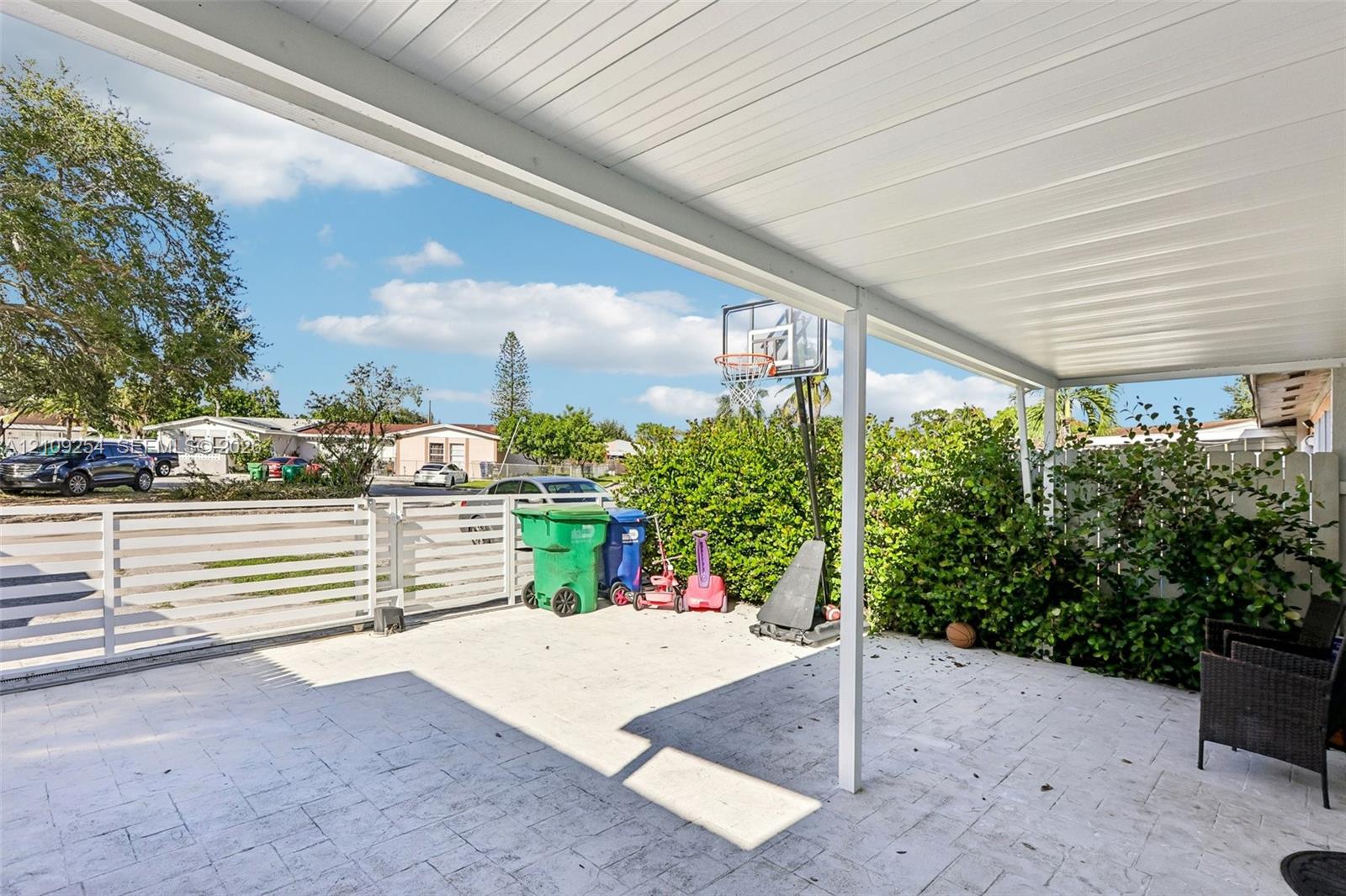 Covered patio featuring a paved floor, a white metal ceiling, and a white horizontal slat fence Covered patio featuring a paved floor, a white metal ceiling, and a white horizontal slat fence