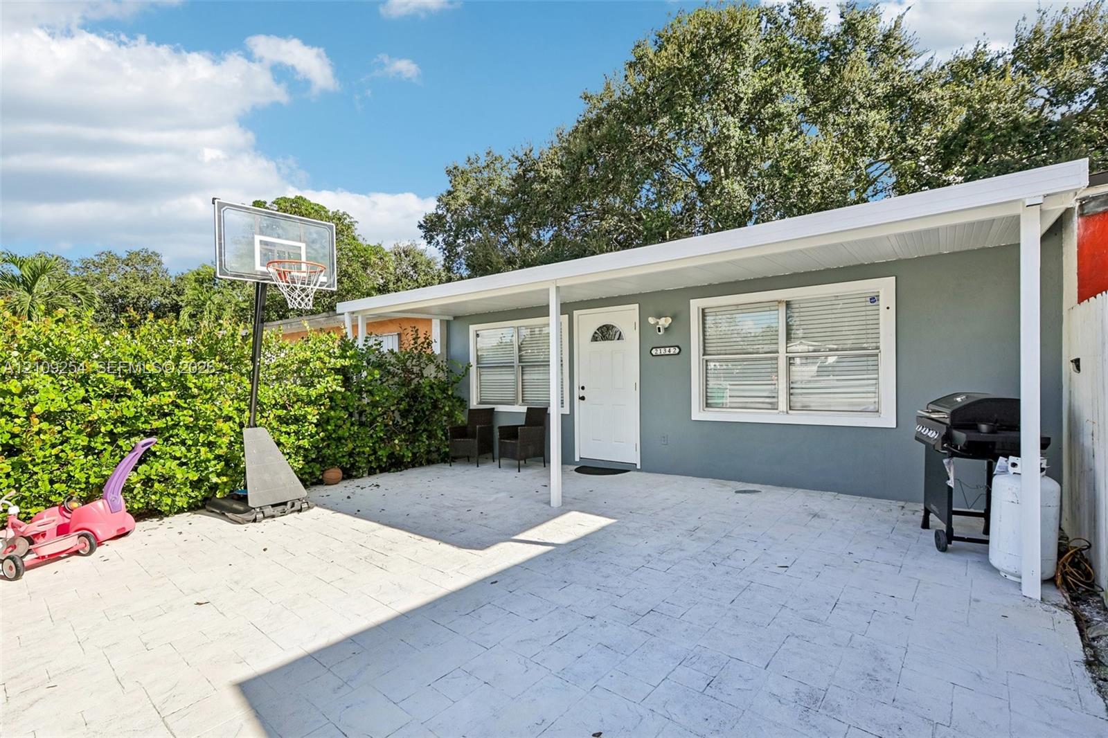 Covered patio featuring stone-paver flooring, light-colored exterior wall finish, and white-framed windows Covered patio featuring stone-paver flooring, light-colored exterior wall finish, and white-framed windows