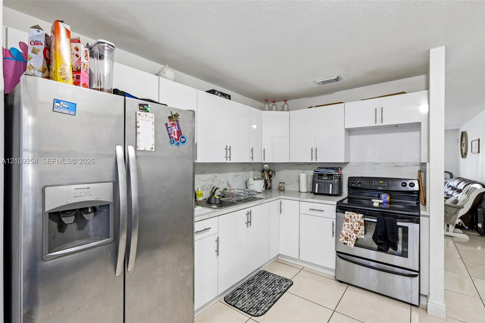 Kitchen featuring white cabinetry, stainless steel appliances, and tile flooring