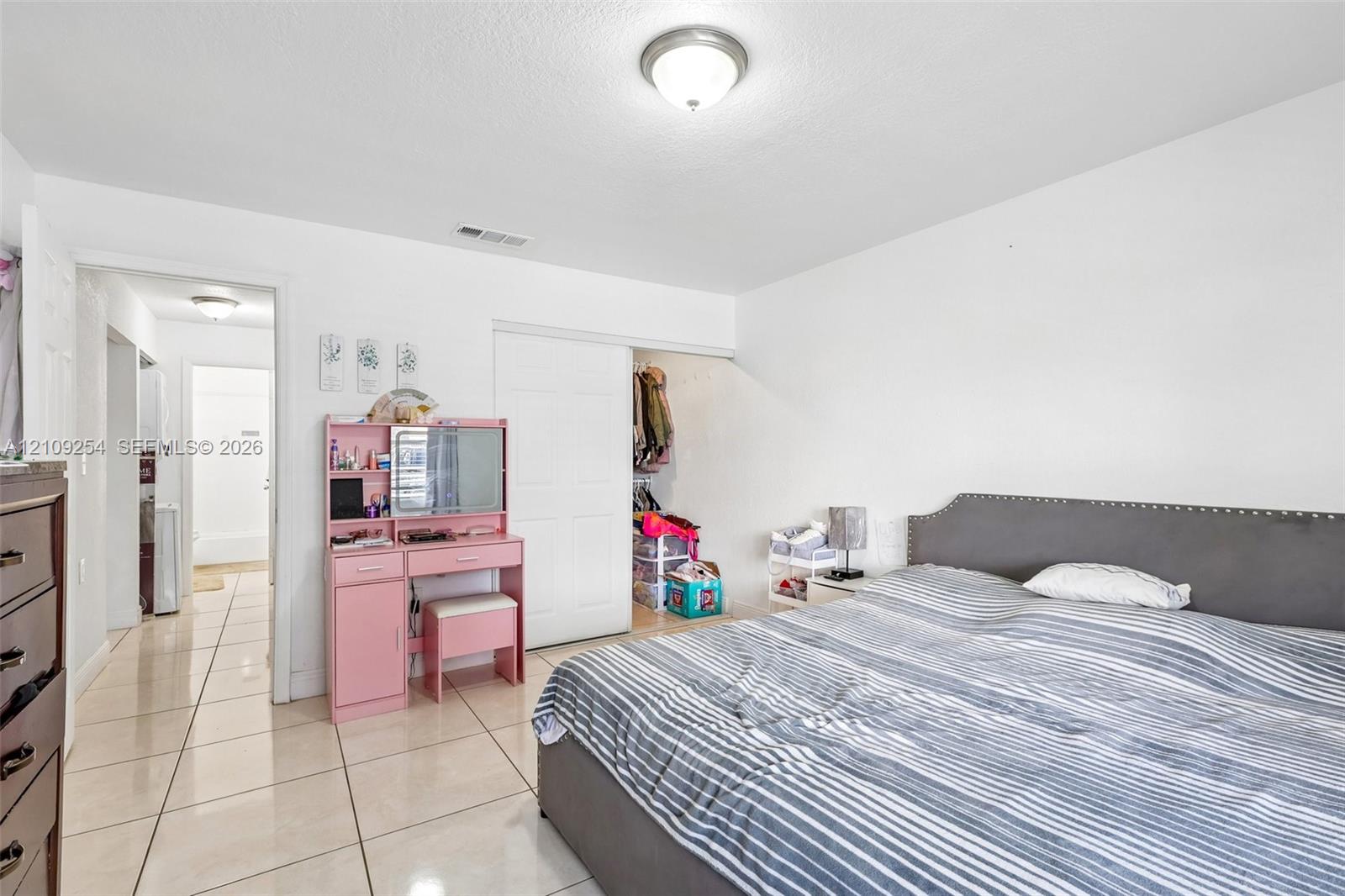 Neutral-toned ceramic tile flooring, semi-flush mount ceiling lighting, and sliding closet doors
