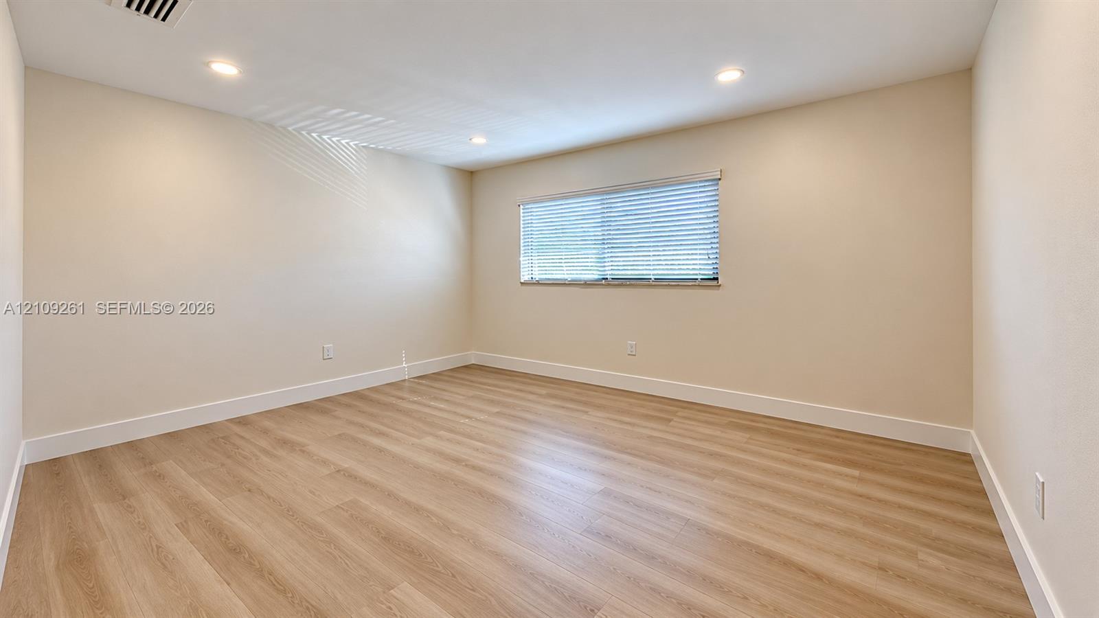 Neutral-toned interior featuring wood-finish flooring, recessed lighting, and horizontal window blinds