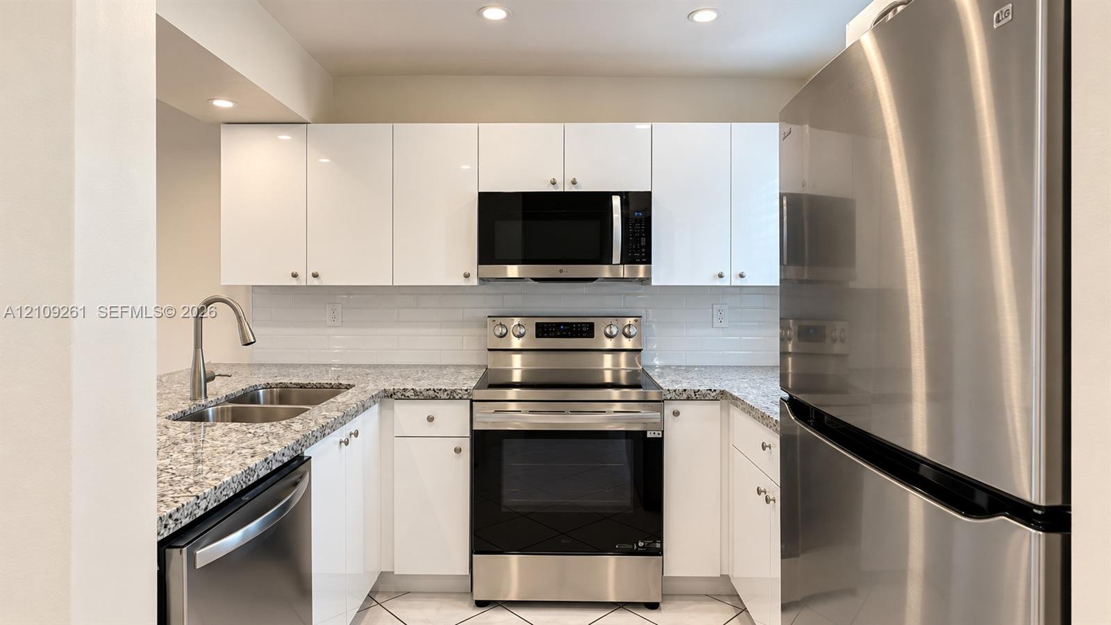 Kitchen featuring white gloss cabinetry, stone-finish countertops, subway tile backsplash, stainless steel appliances, and recessed lighting