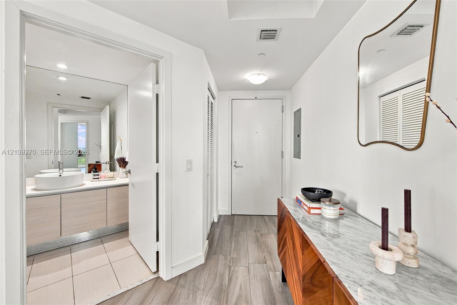 Entryway featuring wood-finish flooring, a wall-mounted mirror, and louvered closet doors