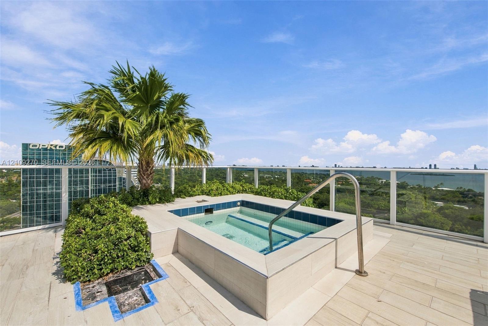 Rooftop terrace featuring an elevated spa with tile surround, glass panel railing, and integrated landscaping