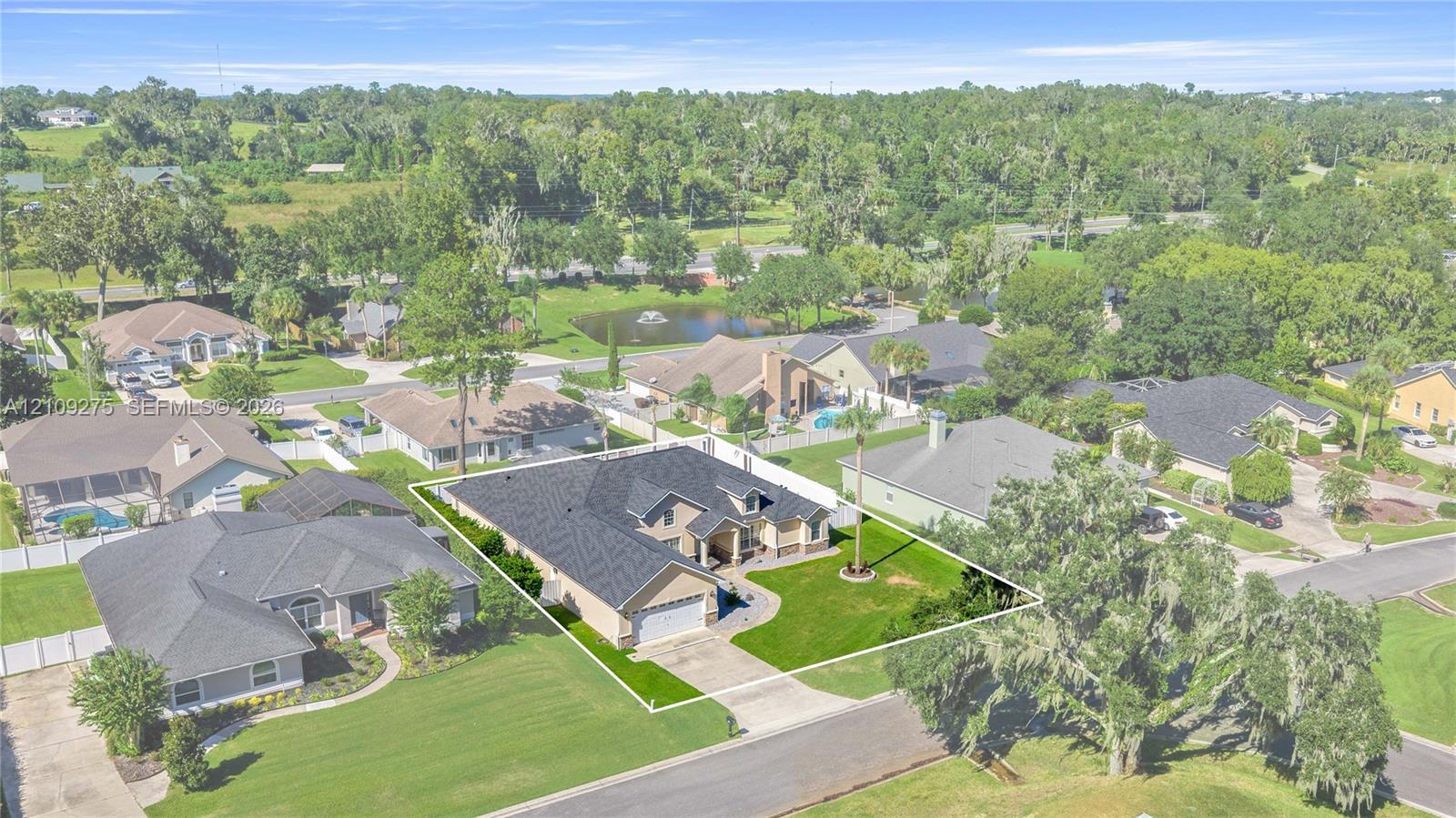 Single-story residence featuring a multi-gabled shingle roof, a two-car garage, brick facade detailing, and a manicured front lawn