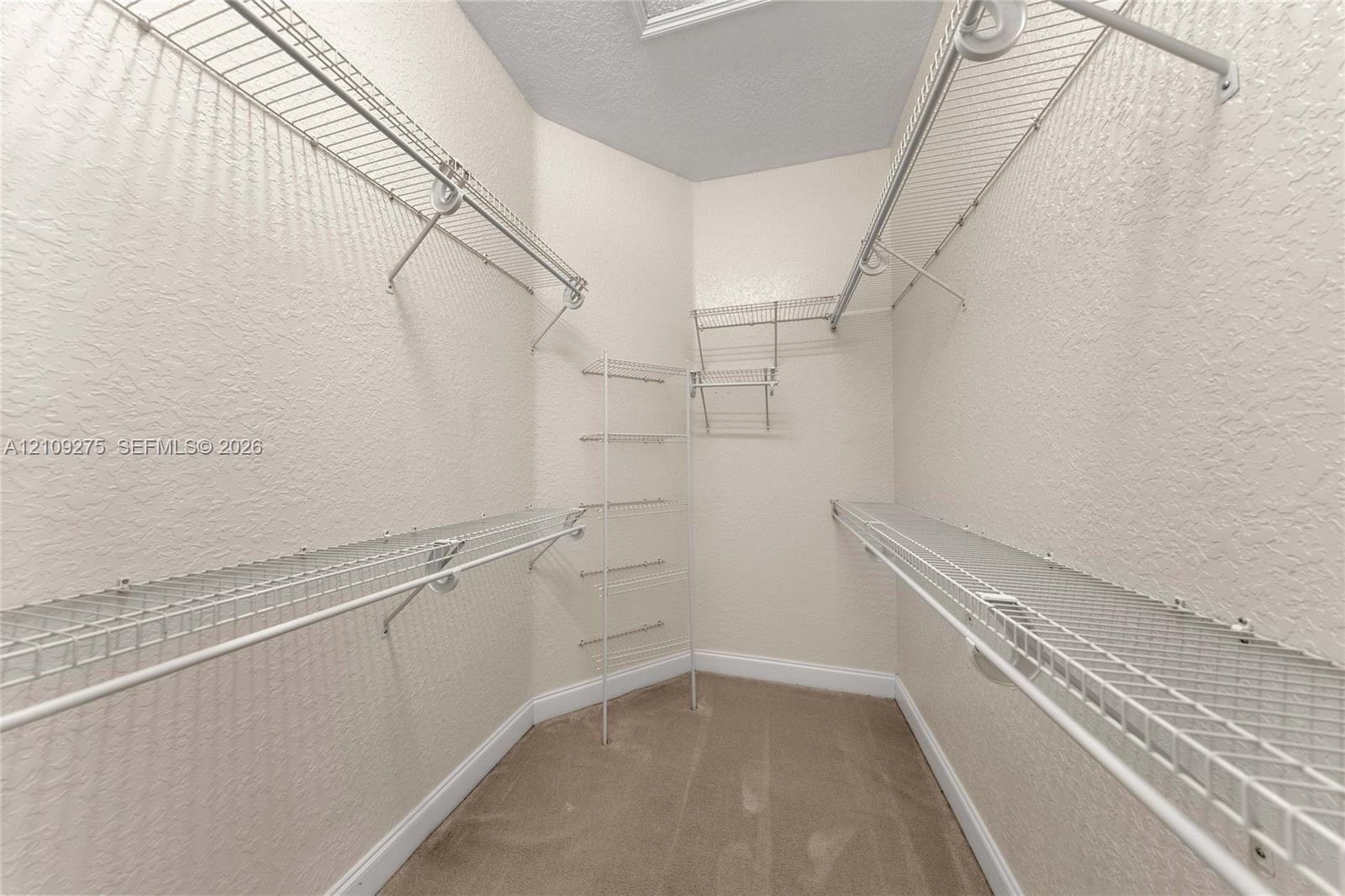 Walk-in storage space featuring multi-level wire shelving and wall-to-wall carpeting