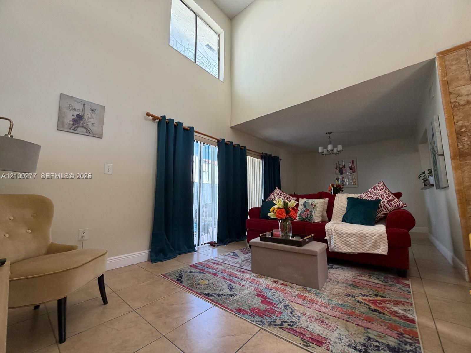 Vaulted ceiling, ceramic tile flooring, vertical sliding glass door, and multi-light chandelier