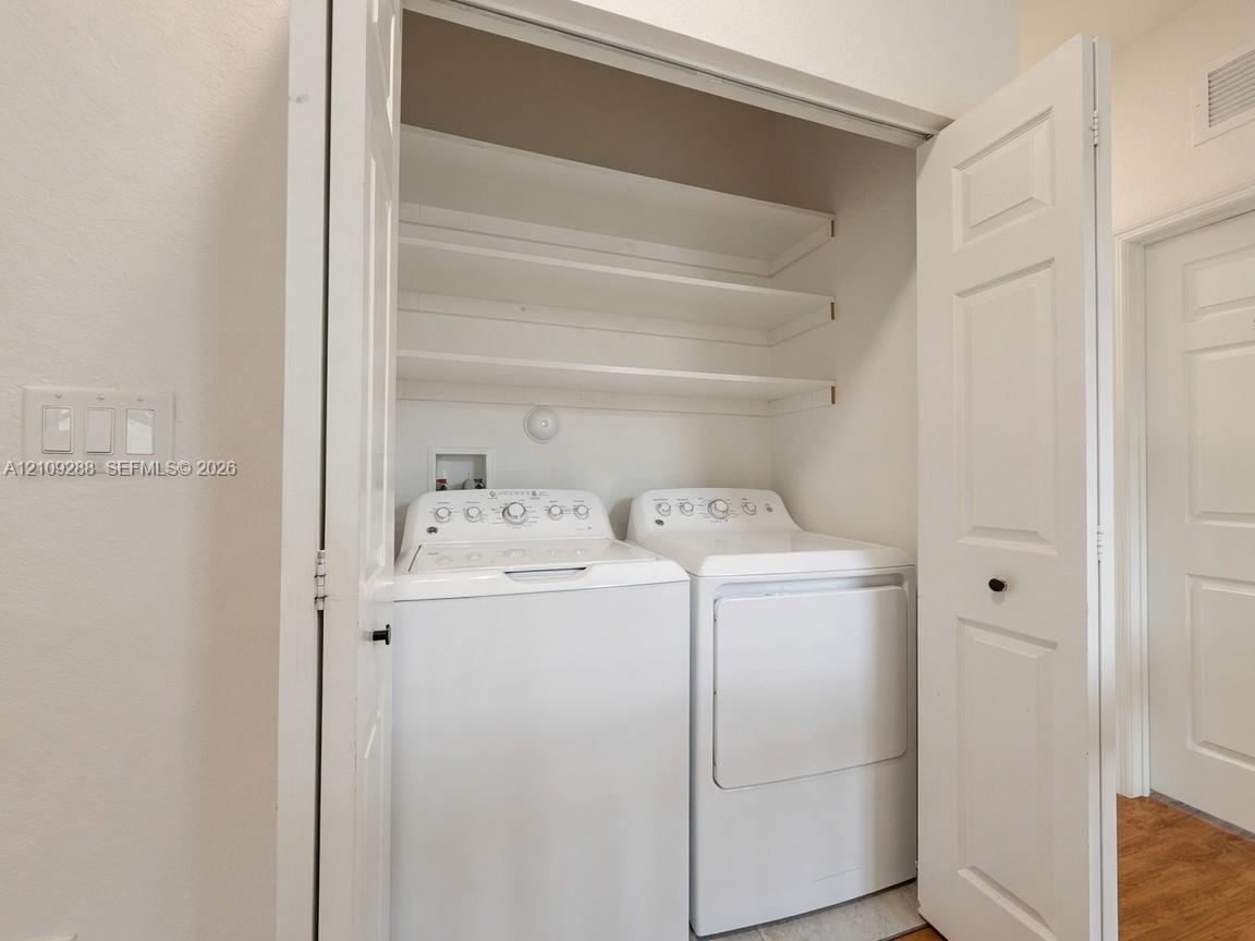 Laundry closet featuring white bi-fold doors and overhead shelving