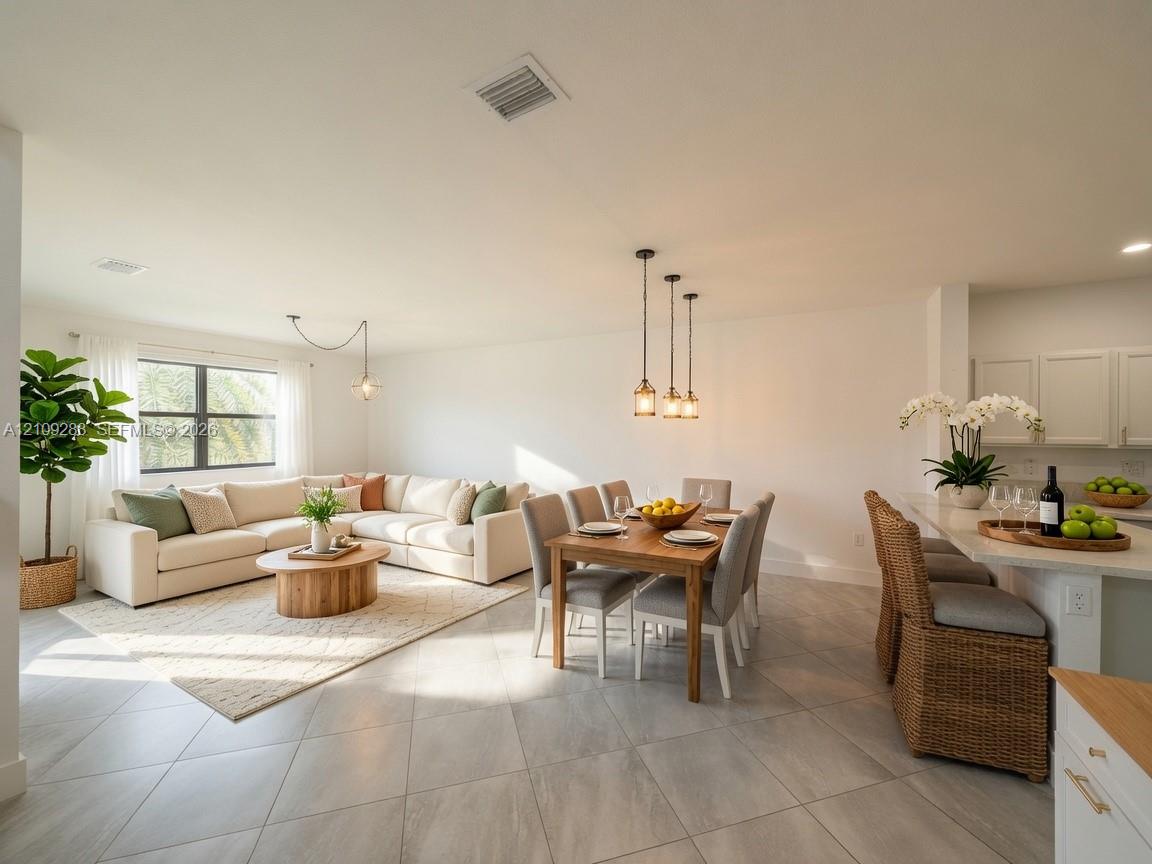 Open-concept interior featuring large-format tile flooring, recessed lighting, three-pendant dining illumination, and a breakfast bar with stone-finish countertops