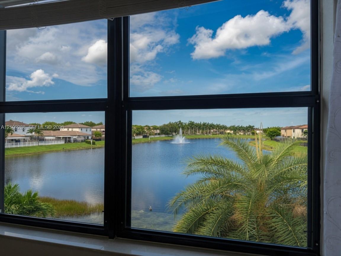 Large multi-pane windows providing natural light and exterior scenery of a lake, fountain, and palm trees