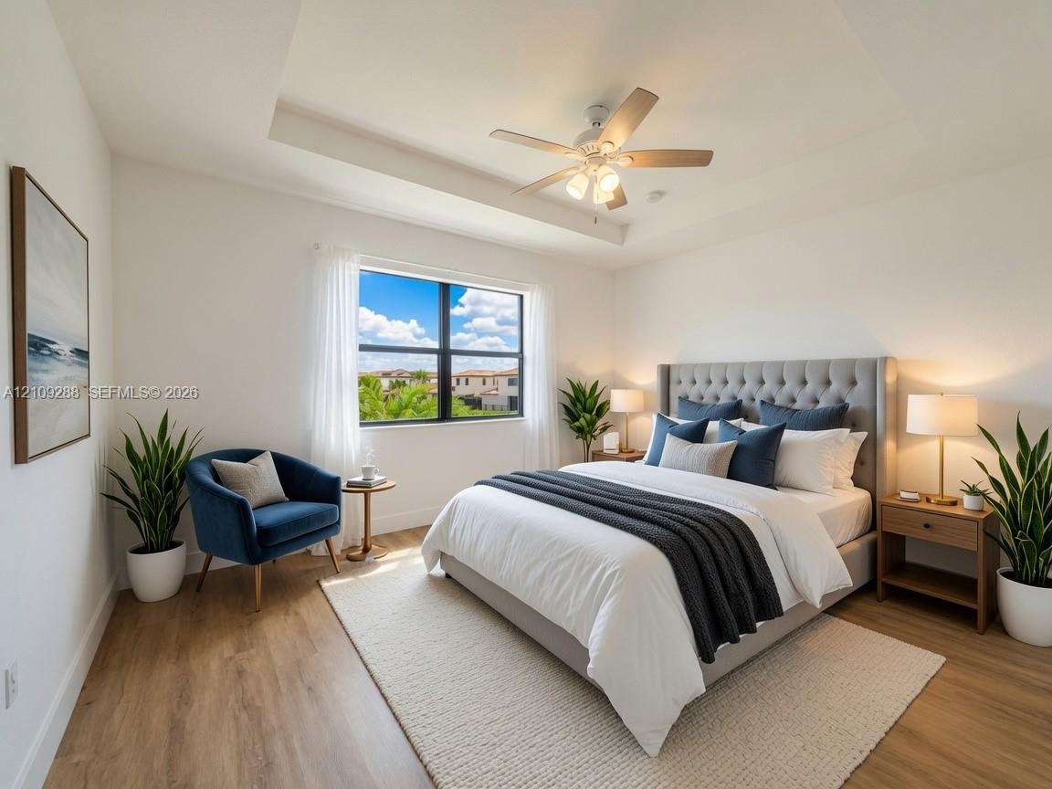 Tray ceiling featuring a central multi-blade ceiling fan with integrated lighting, wood-finish flooring, and window with black frame