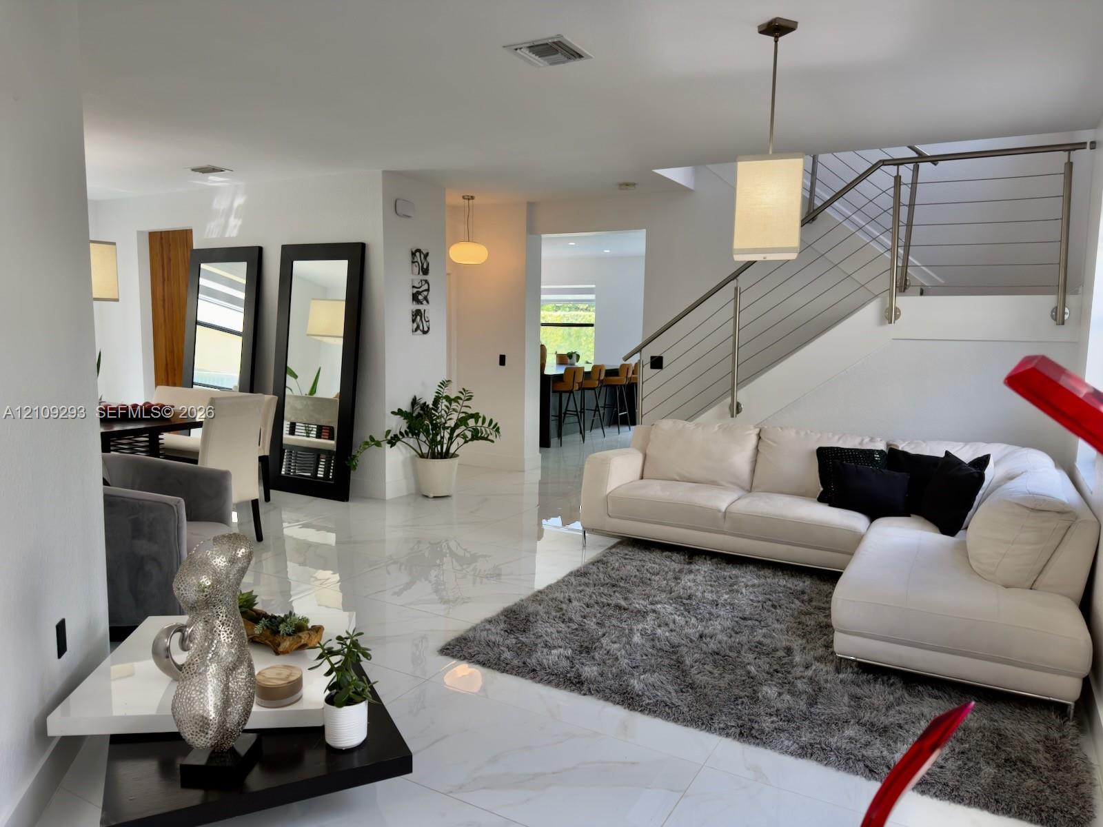 Polished tile flooring, recessed lighting, and a cable-railing staircase featuring a sleek metal handrail