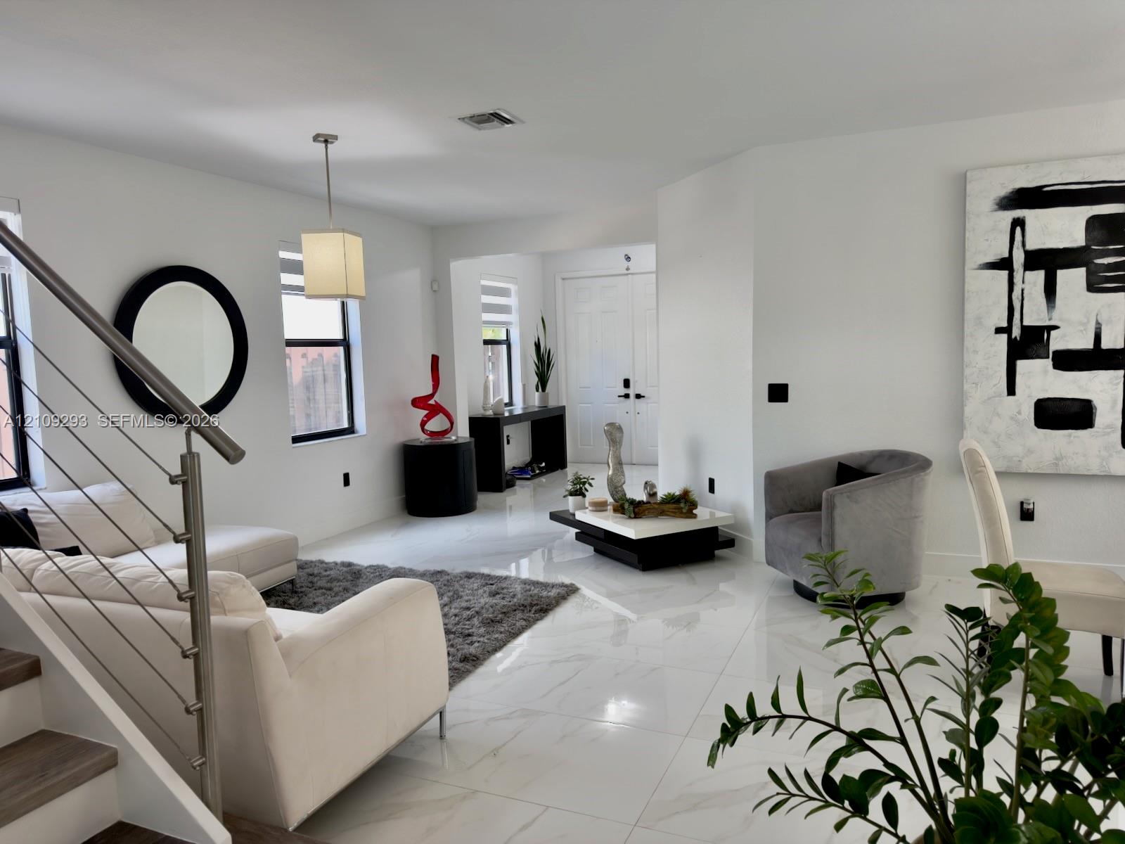 Open-concept interior featuring large-format tile flooring, metal cable railing, and double-door entryway