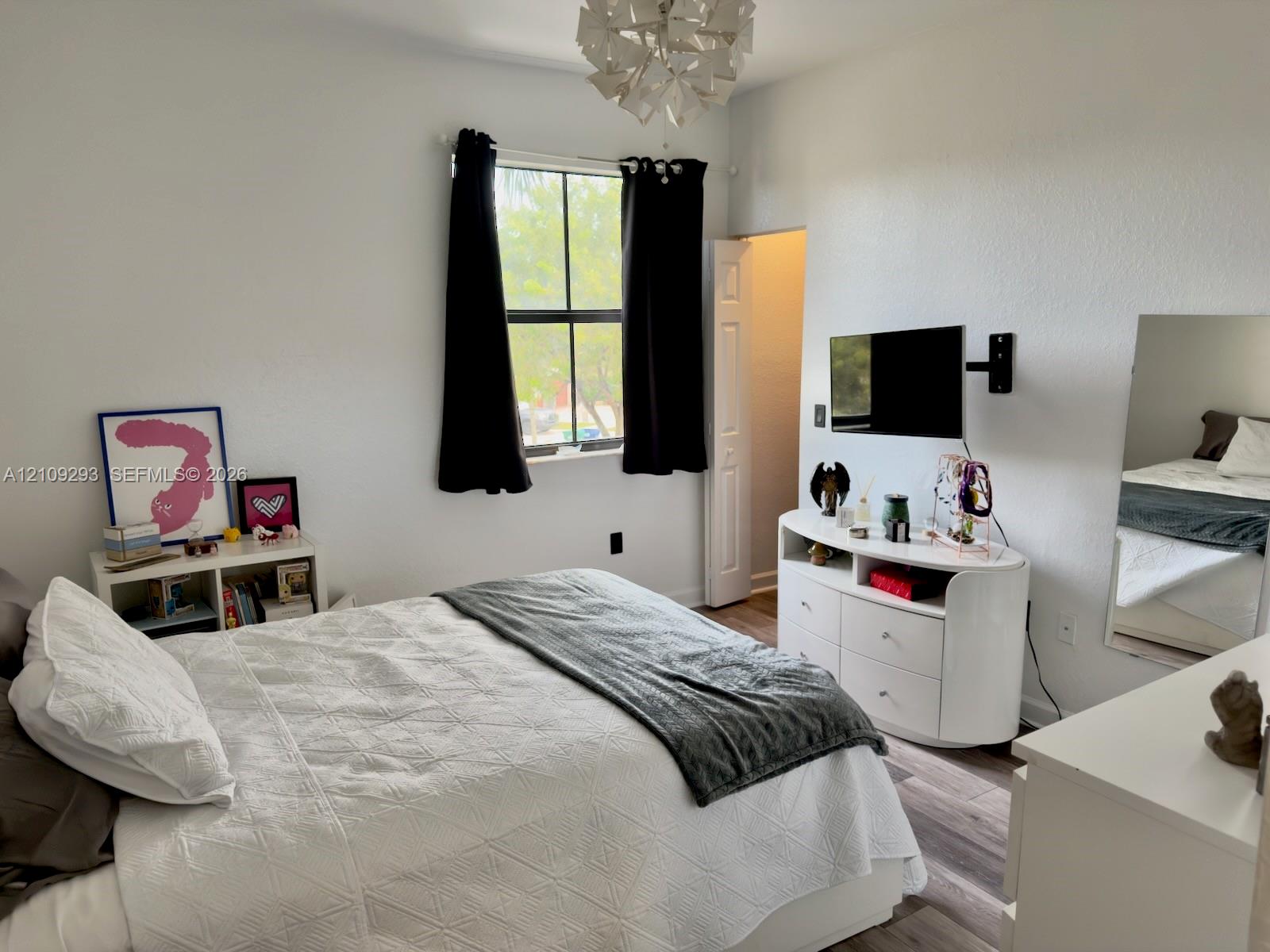 Room featuring wood-finish flooring, a multi-pane window, and a modern geometric pendant light fixture
