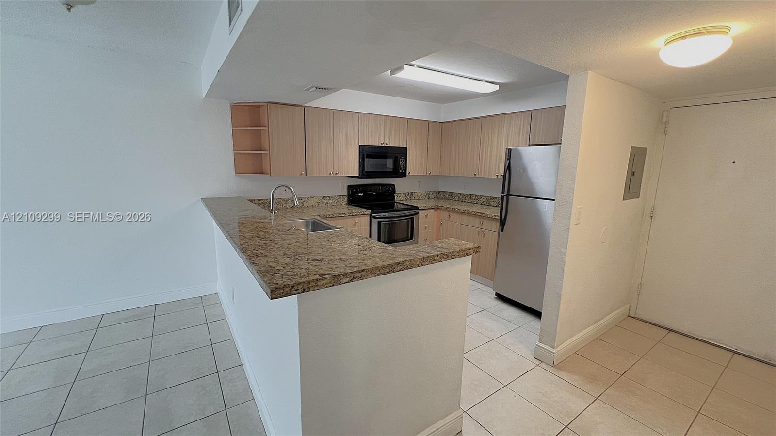 Kitchen featuring light-finish cabinetry, stone-surface countertops, tile flooring, and stainless steel appliances