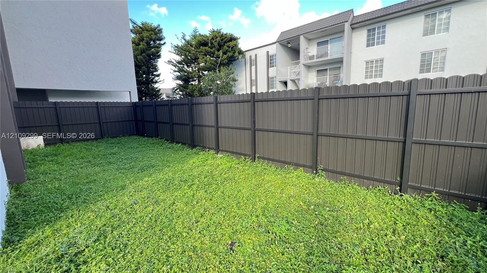 Private outdoor space featuring a dark-toned vertical slat privacy fence and a grassy yard