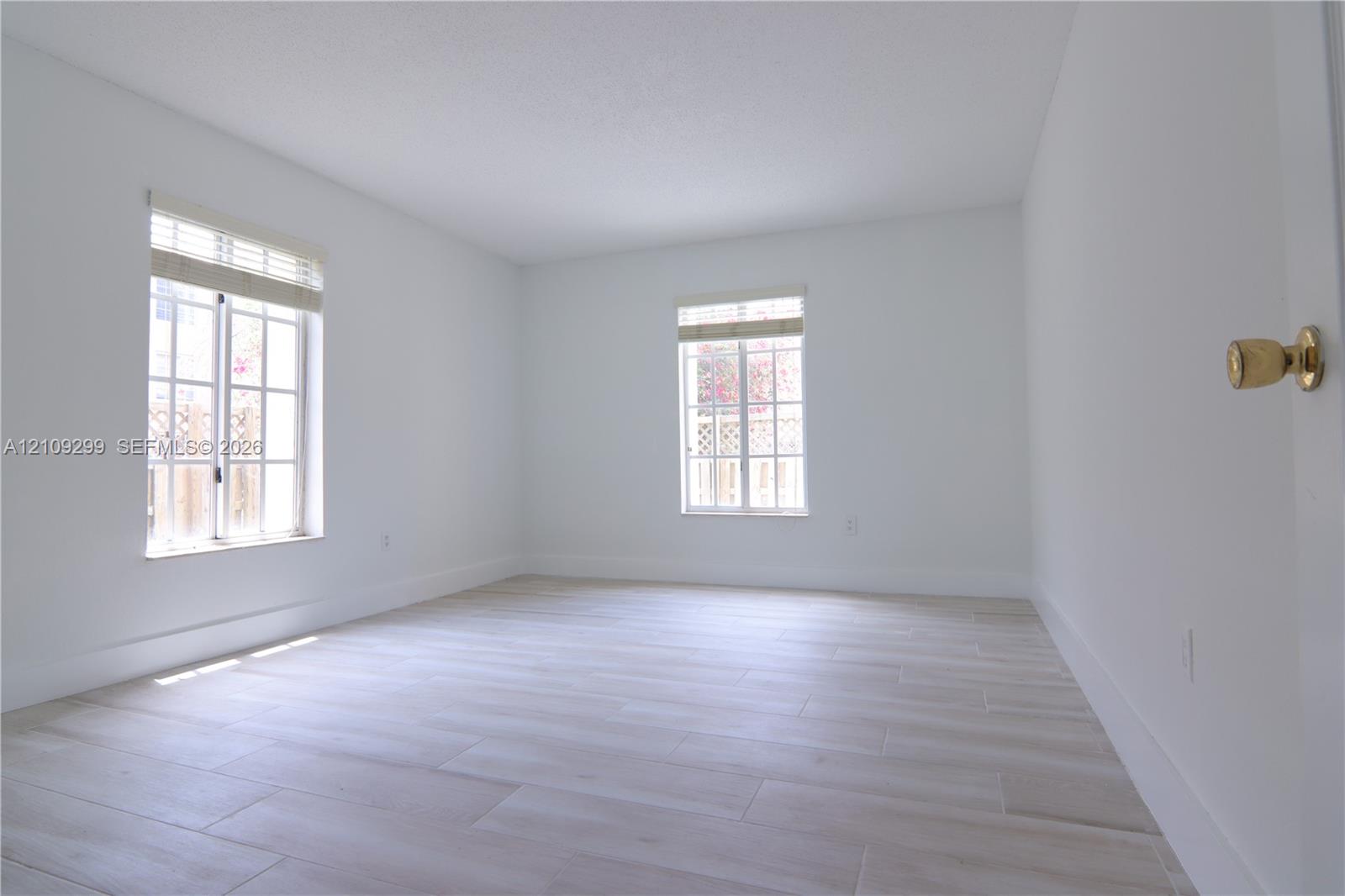 Interior room featuring neutral wall finishes, wood-finish flooring, and two windows with integrated grid patterns