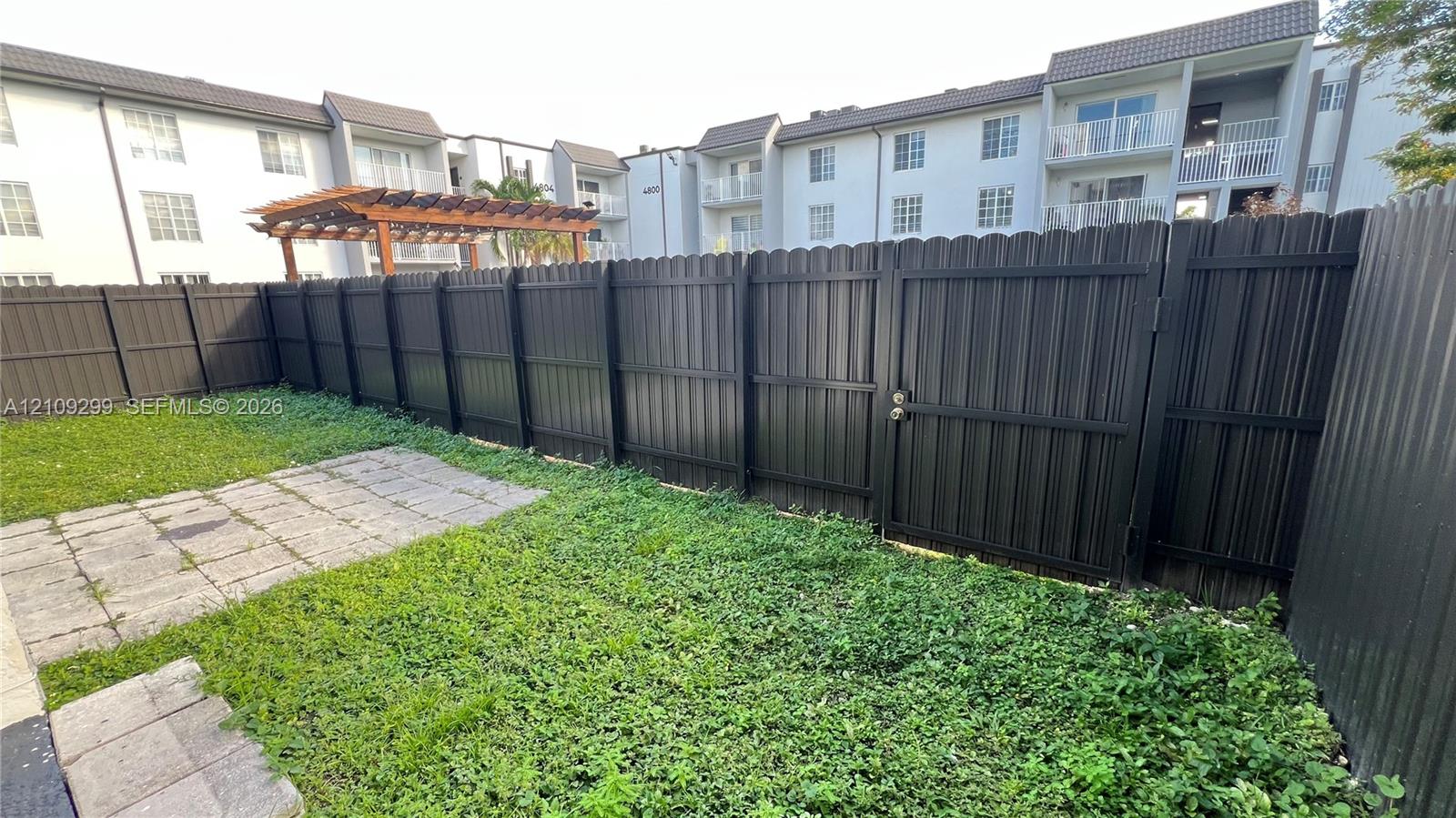 Private outdoor space featuring a dark-toned privacy fence, a gated entry, and a paved patio surface