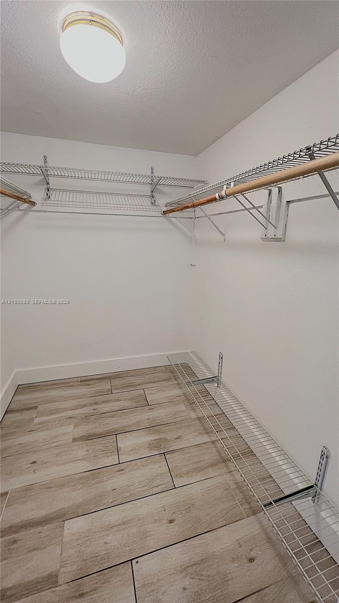 Walk-in closet featuring wood-finish tile flooring, multi-level wire shelving, integrated hanging rods, and a ceiling-mounted light fixture