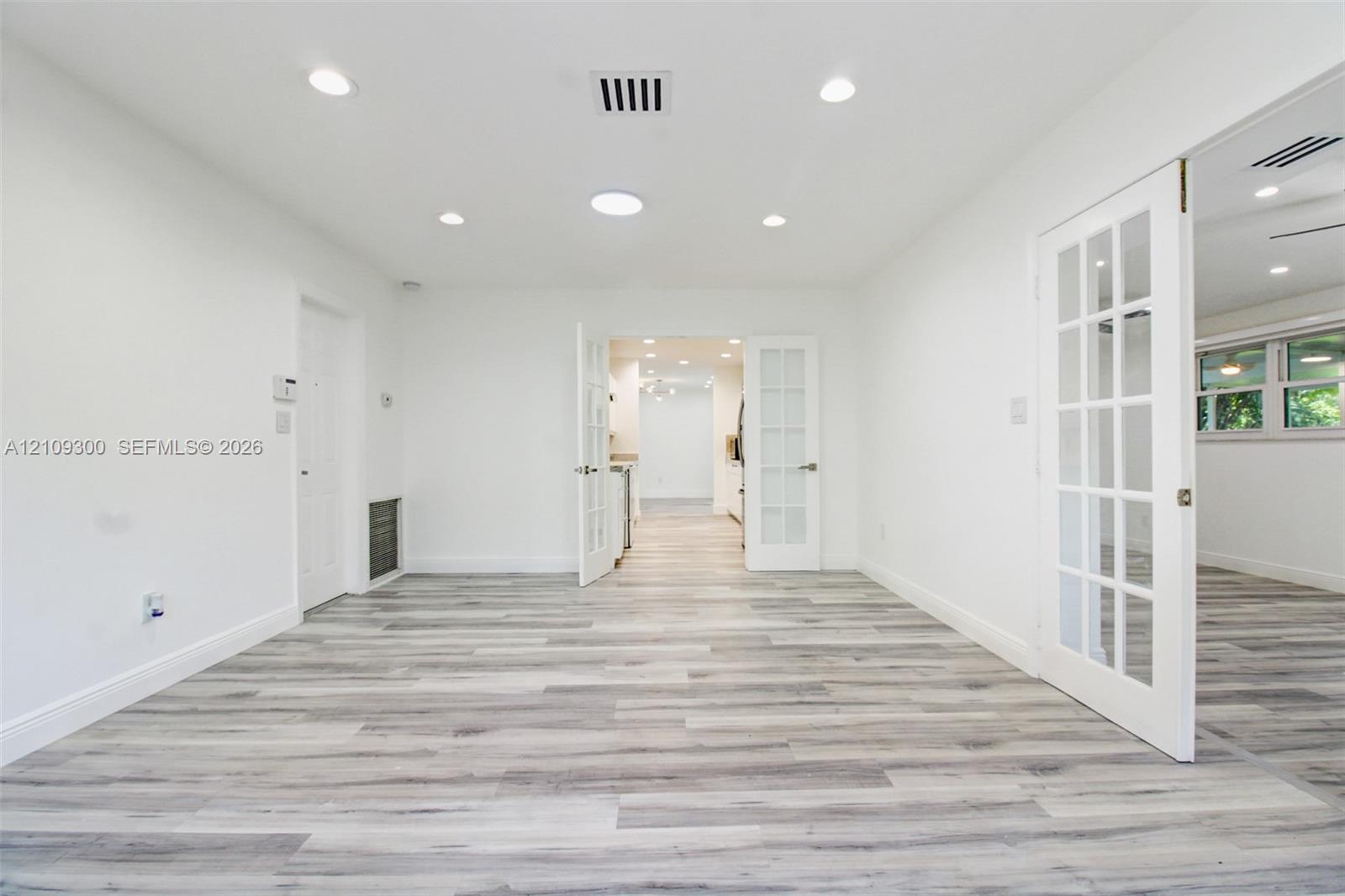 Wood-finish flooring, recessed lighting, and white-paned French doors