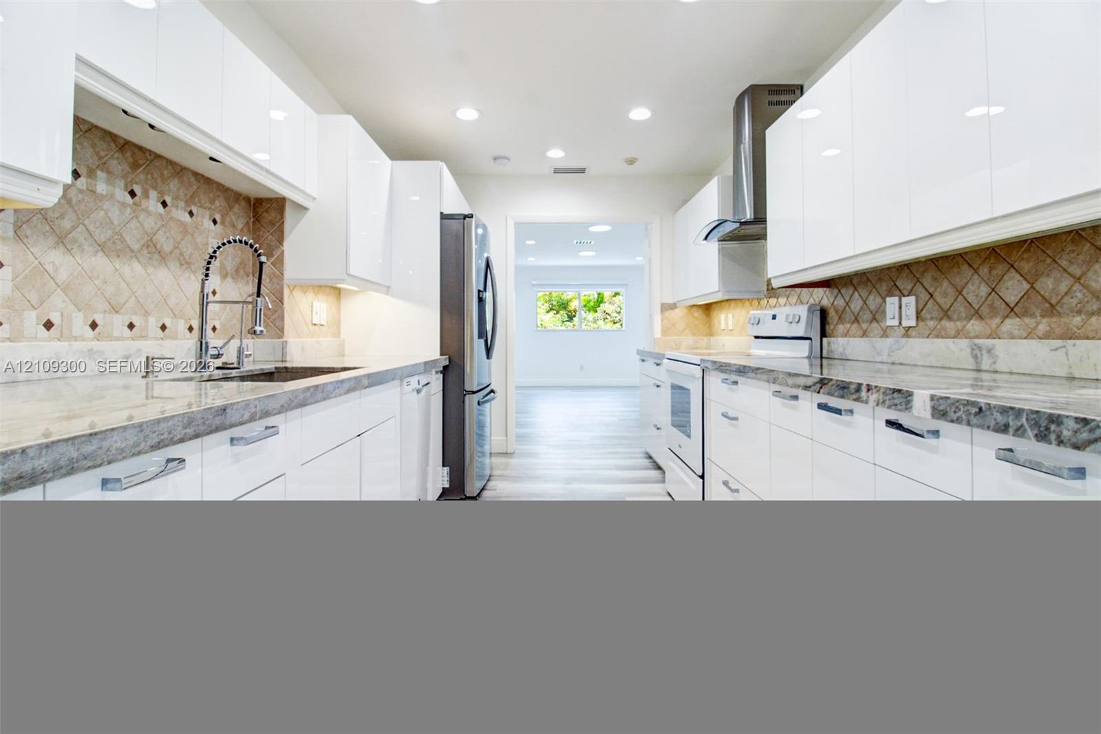 High-gloss white cabinetry, stone countertops, diamond-pattern tile backsplash, stainless steel appliances, and recessed lighting