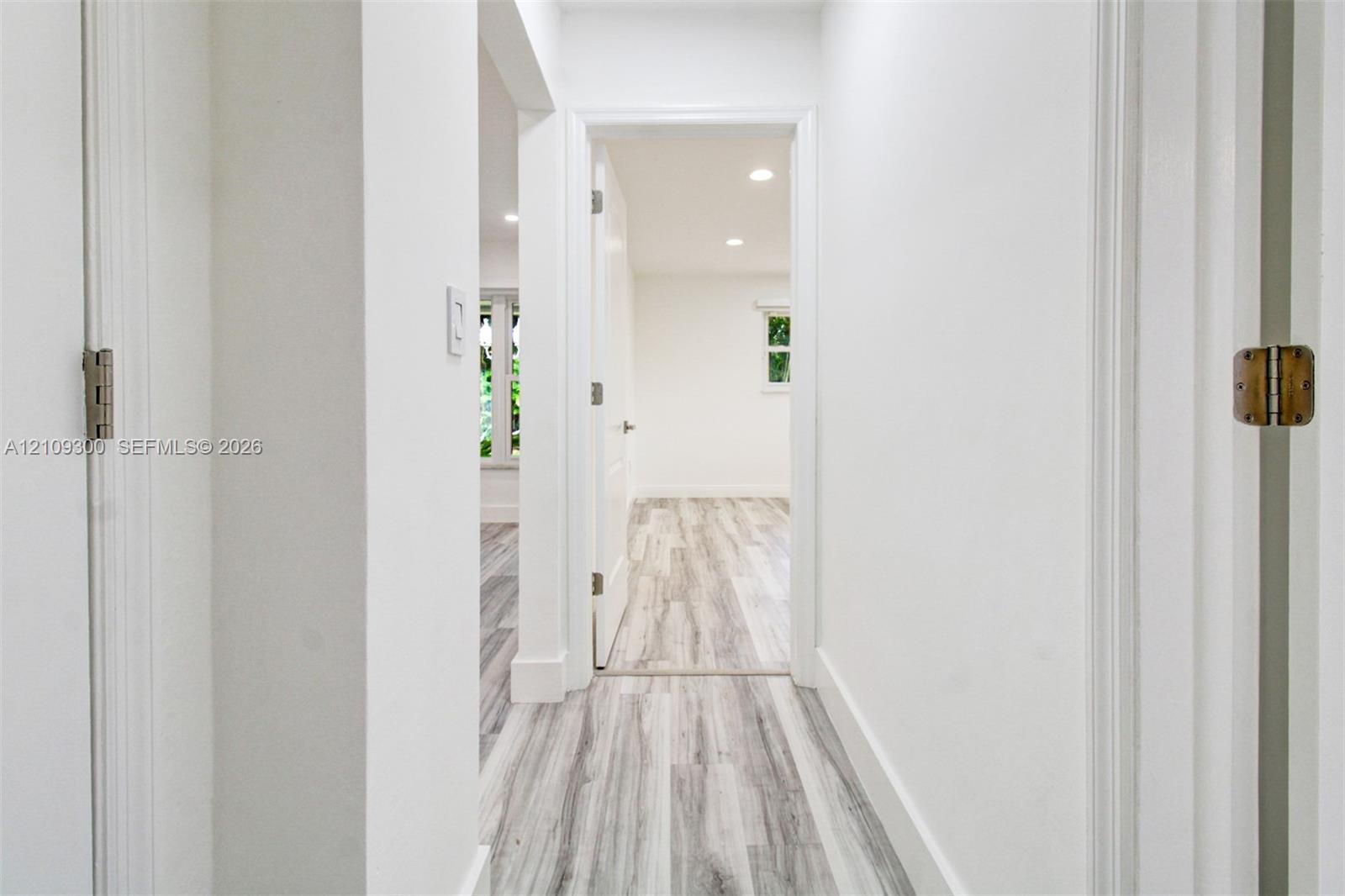 Interior hallway featuring neutral walls, wood-finish flooring, recessed lighting, and white door casings