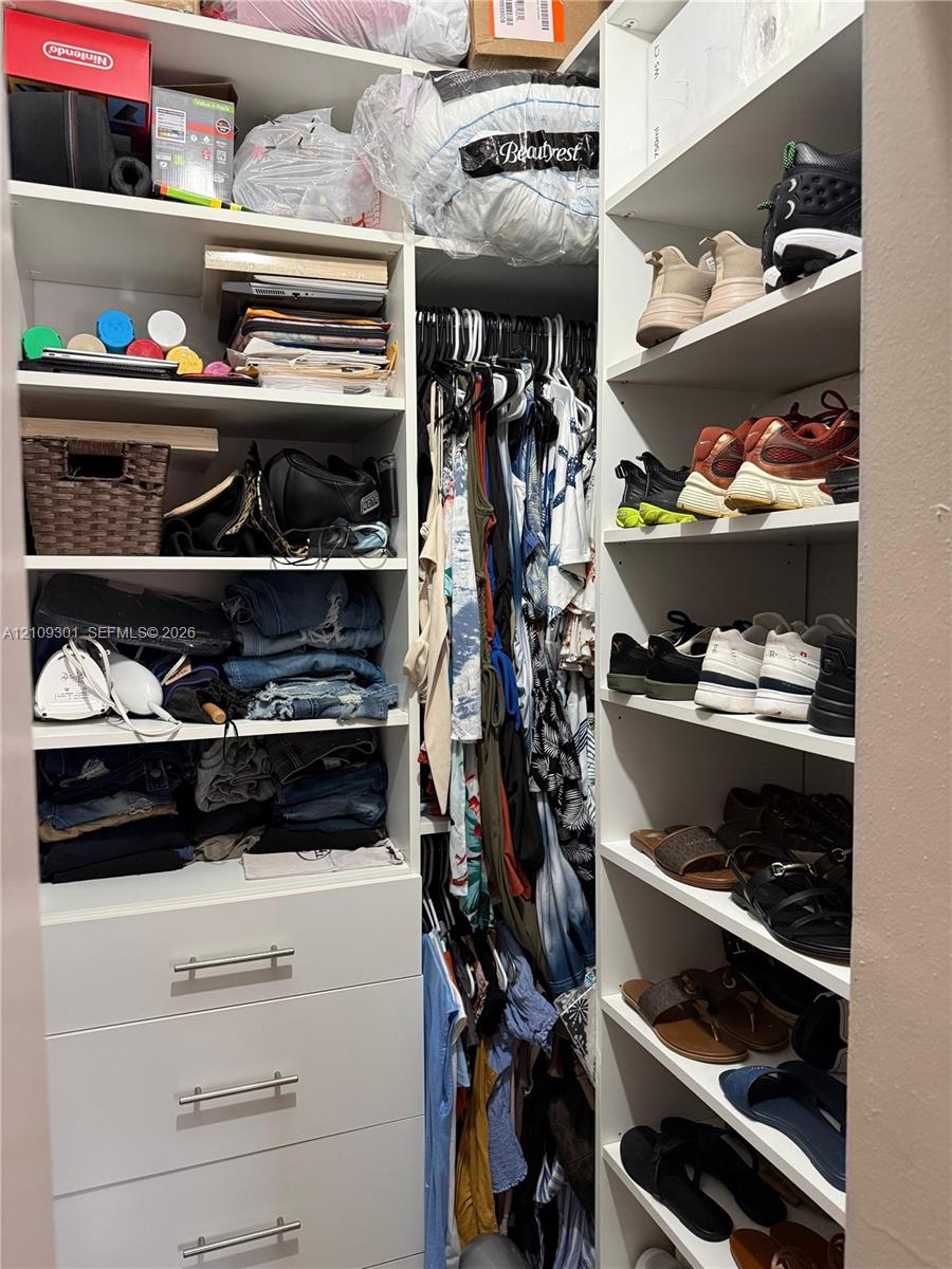 Custom closet organization system featuring white built-in shelving, multiple open storage compartments, and three lower drawers with metal hardware