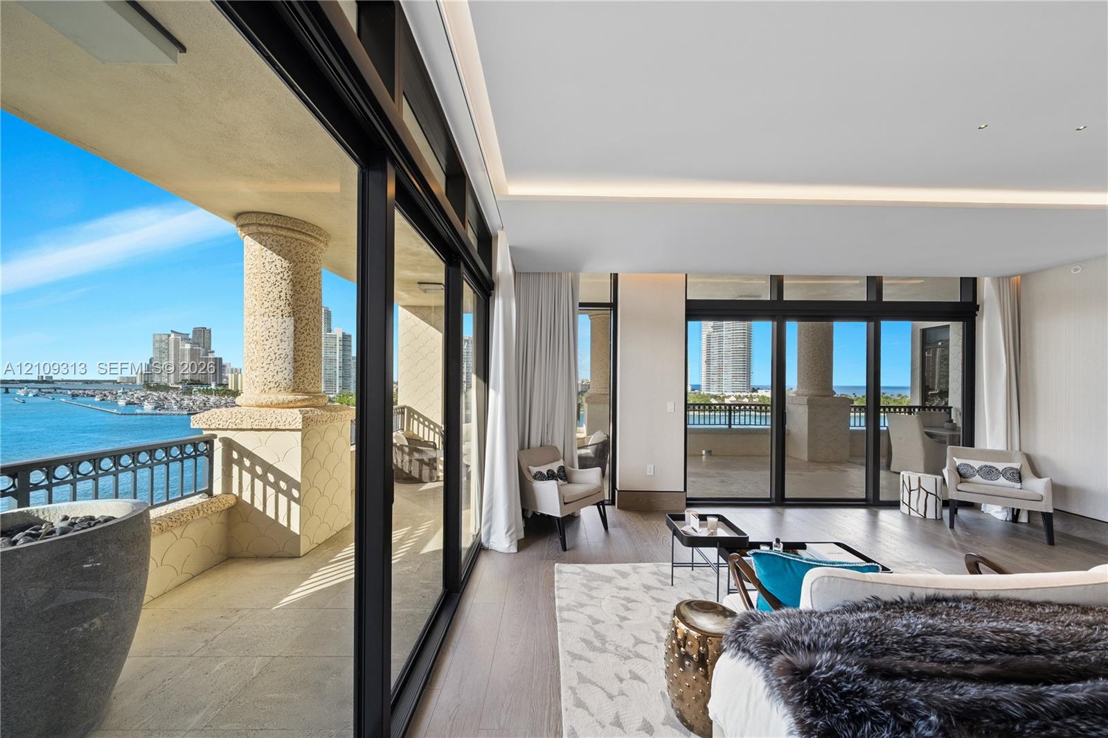 Floor-to-ceiling sliding glass walls, covered balcony with stone-finish pillar, wood-finish flooring, and recessed ceiling lighting