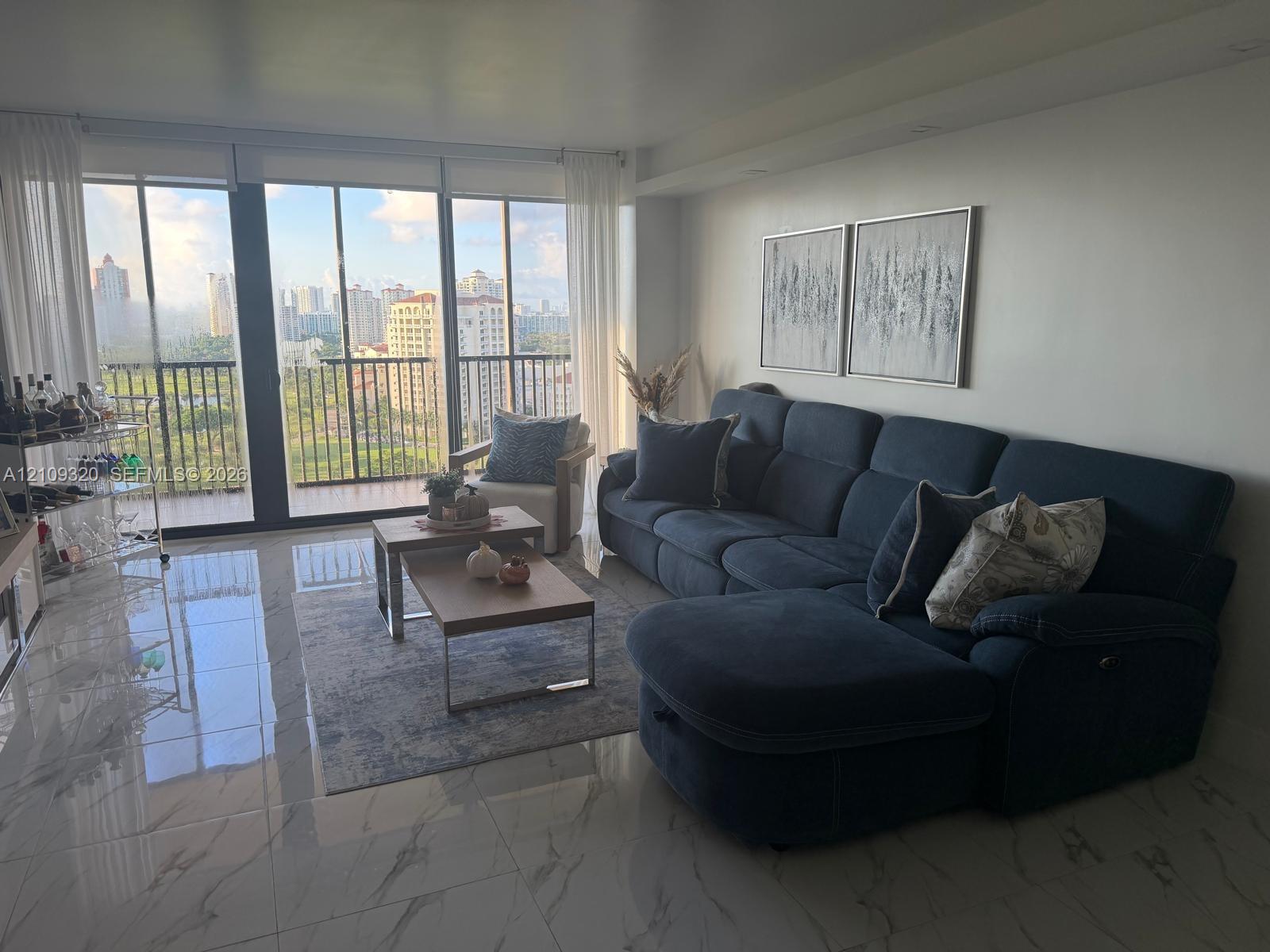 Floor-to-ceiling windows, polished stone-finish flooring, and a private balcony featuring a metal railing