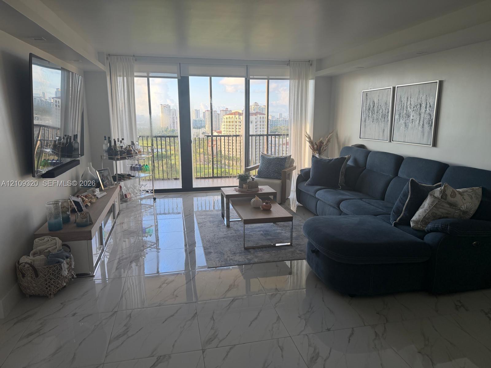 Large format polished stone-finish floor tiles, floor-to-ceiling glass sliding doors, and private balcony with black metal railing