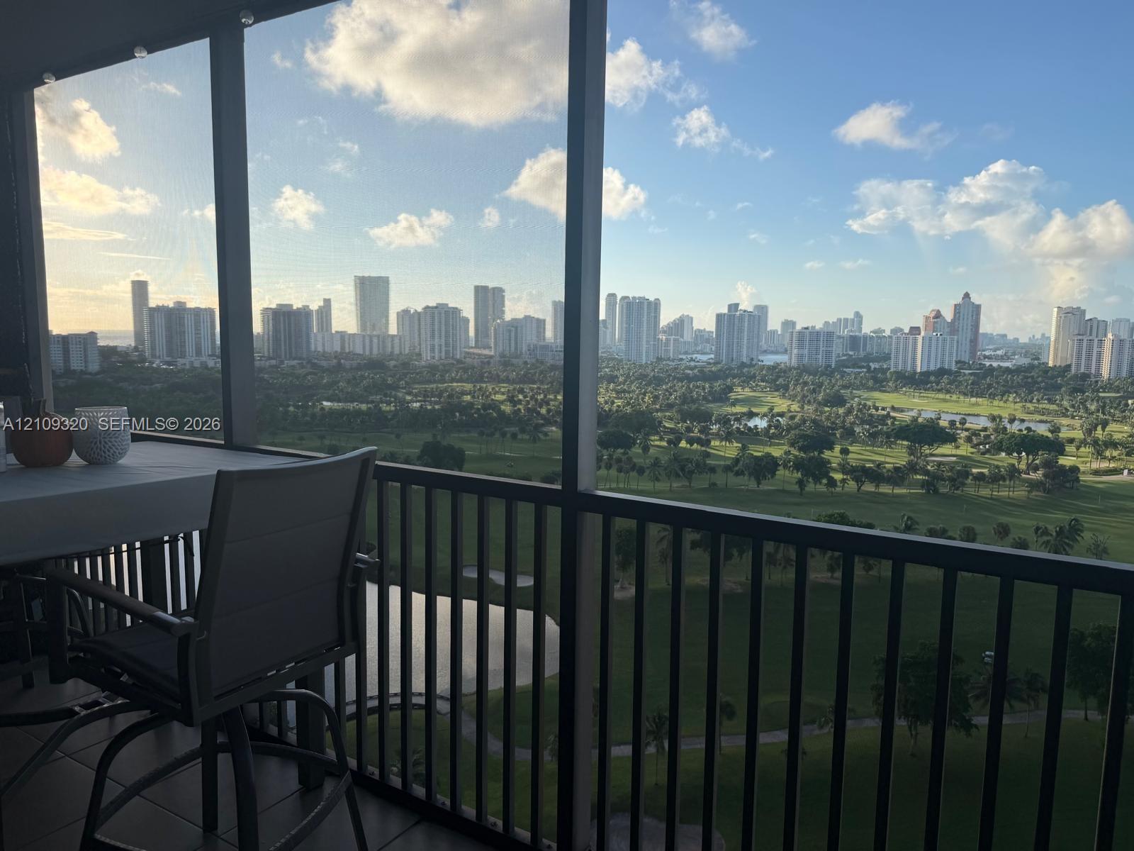 Elevated balcony with a dark-finish metal railing overlooking a golf course and metropolitan skyline