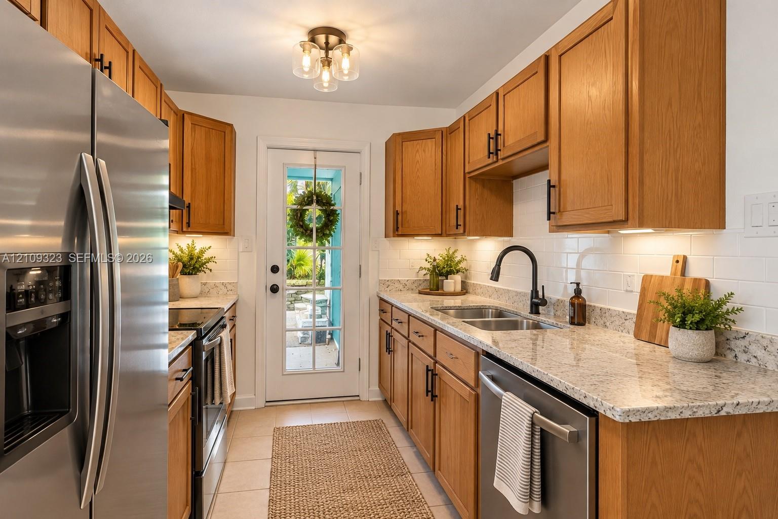 Kitchen featuring wood cabinetry, stone countertops, stainless steel appliances, white subway tile backsplash, and a glass-paneled exterior door