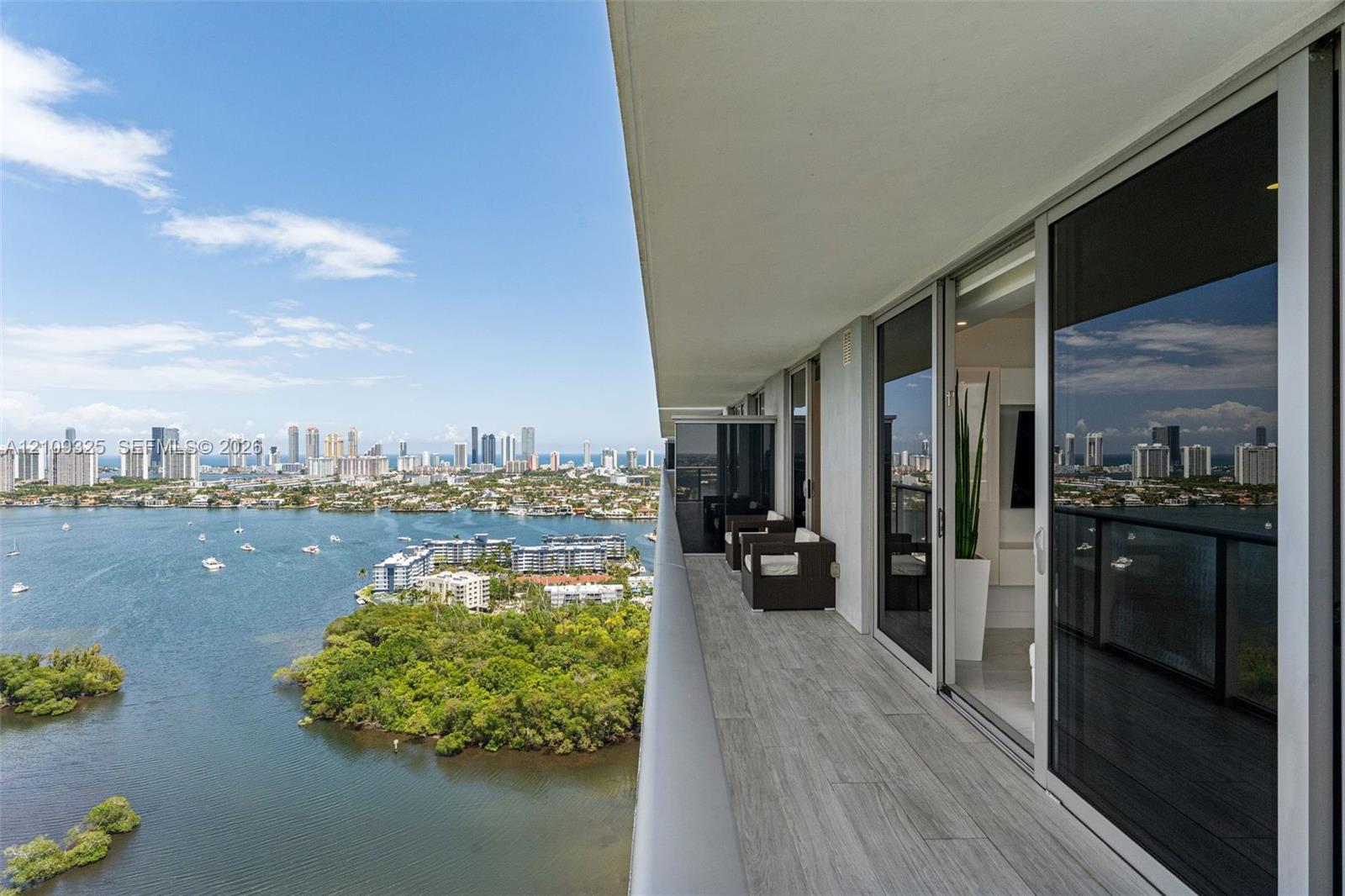 Private balcony featuring wood-finish tile flooring, glass railings, and expansive floor-to-ceiling sliding glass doors