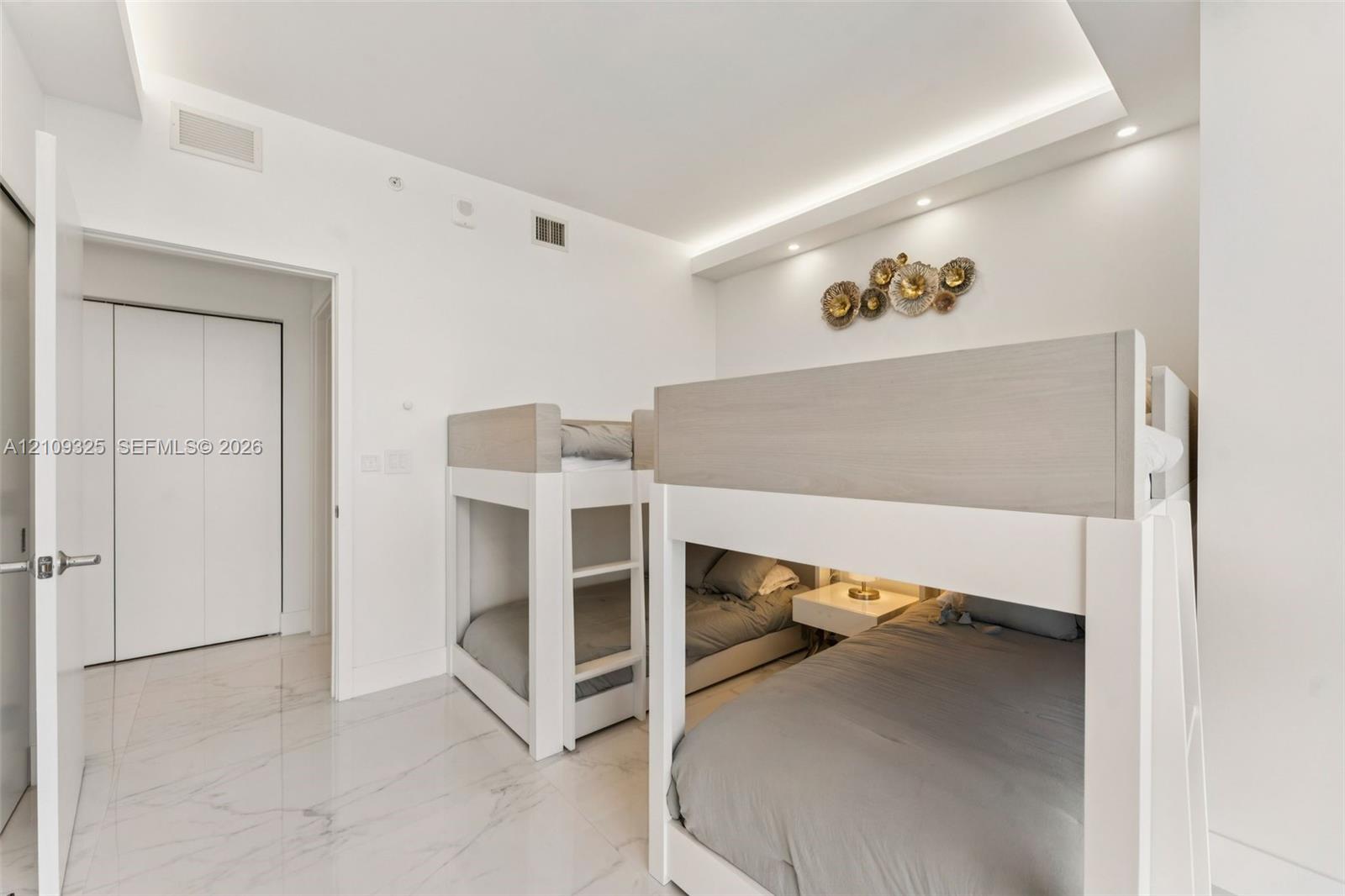 Interior space featuring polished stone-finish flooring, recessed tray ceiling lighting, and double-door closet storage