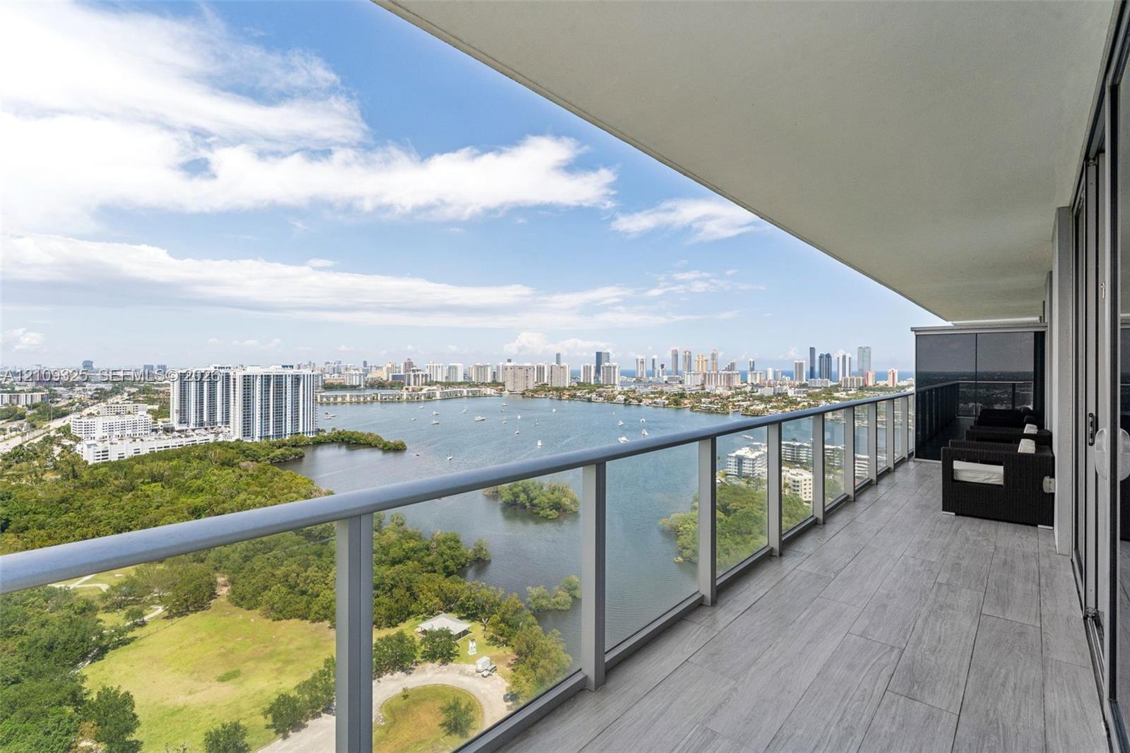 Expansive covered balcony featuring wood-finish tile flooring and a glass panel railing