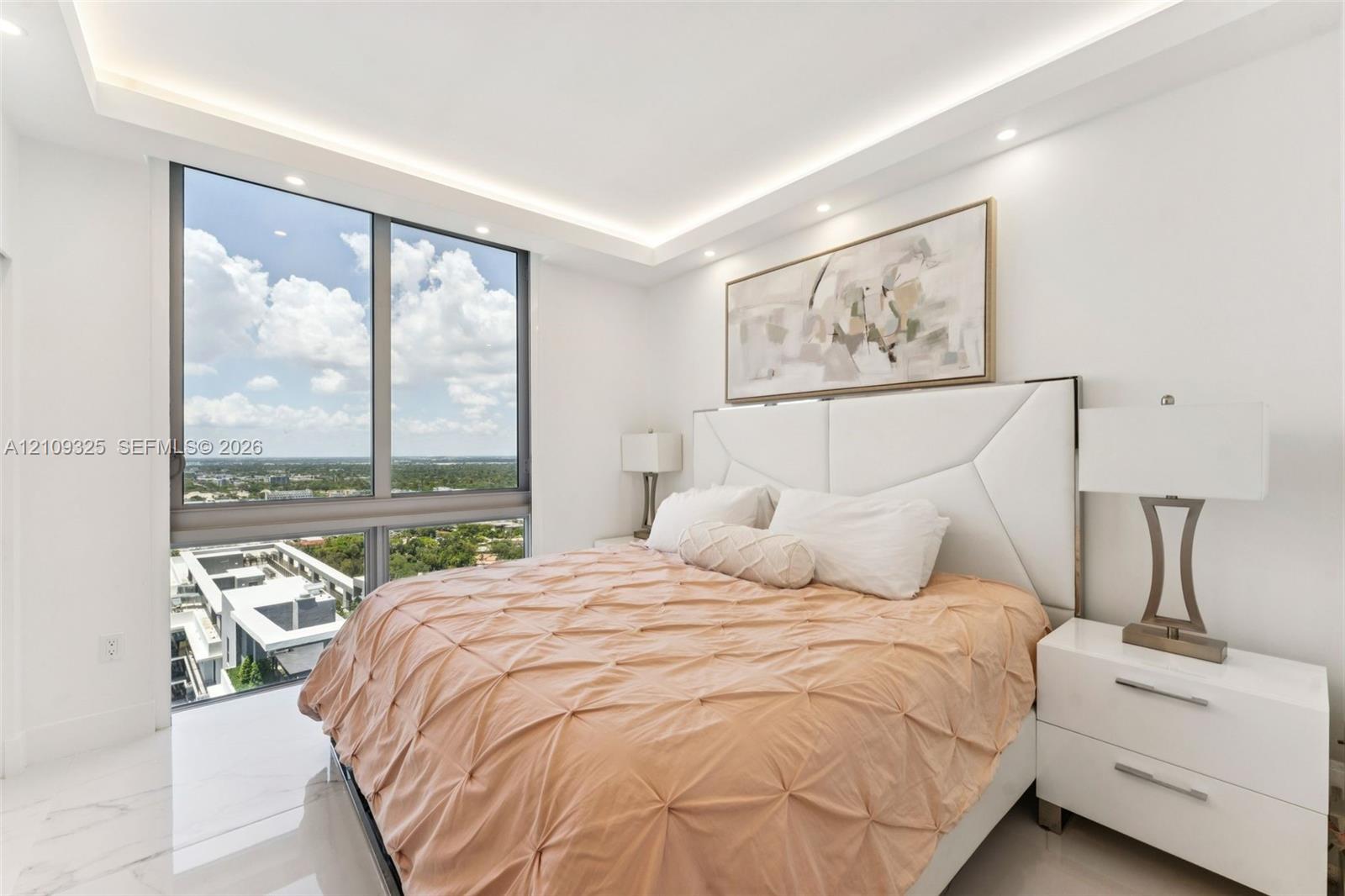 Floor-to-ceiling windows, recessed tray ceiling with integrated lighting, and polished stone-finish flooring